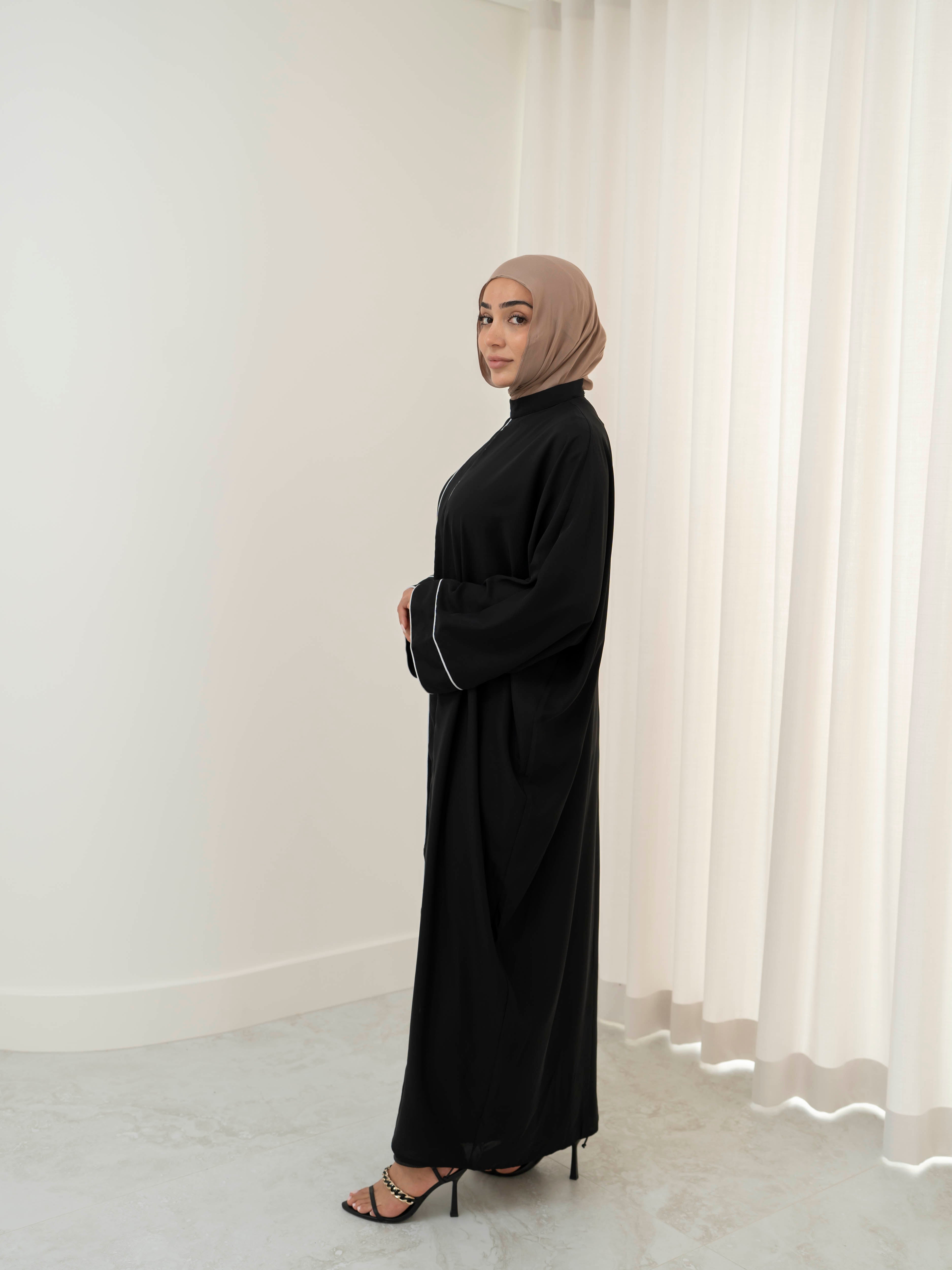 Model wearing the Noor Line abaya featuring a clean silhouette with subtle line detailing, styled for a modest and elegant look suitable for Ramadan and Eid.