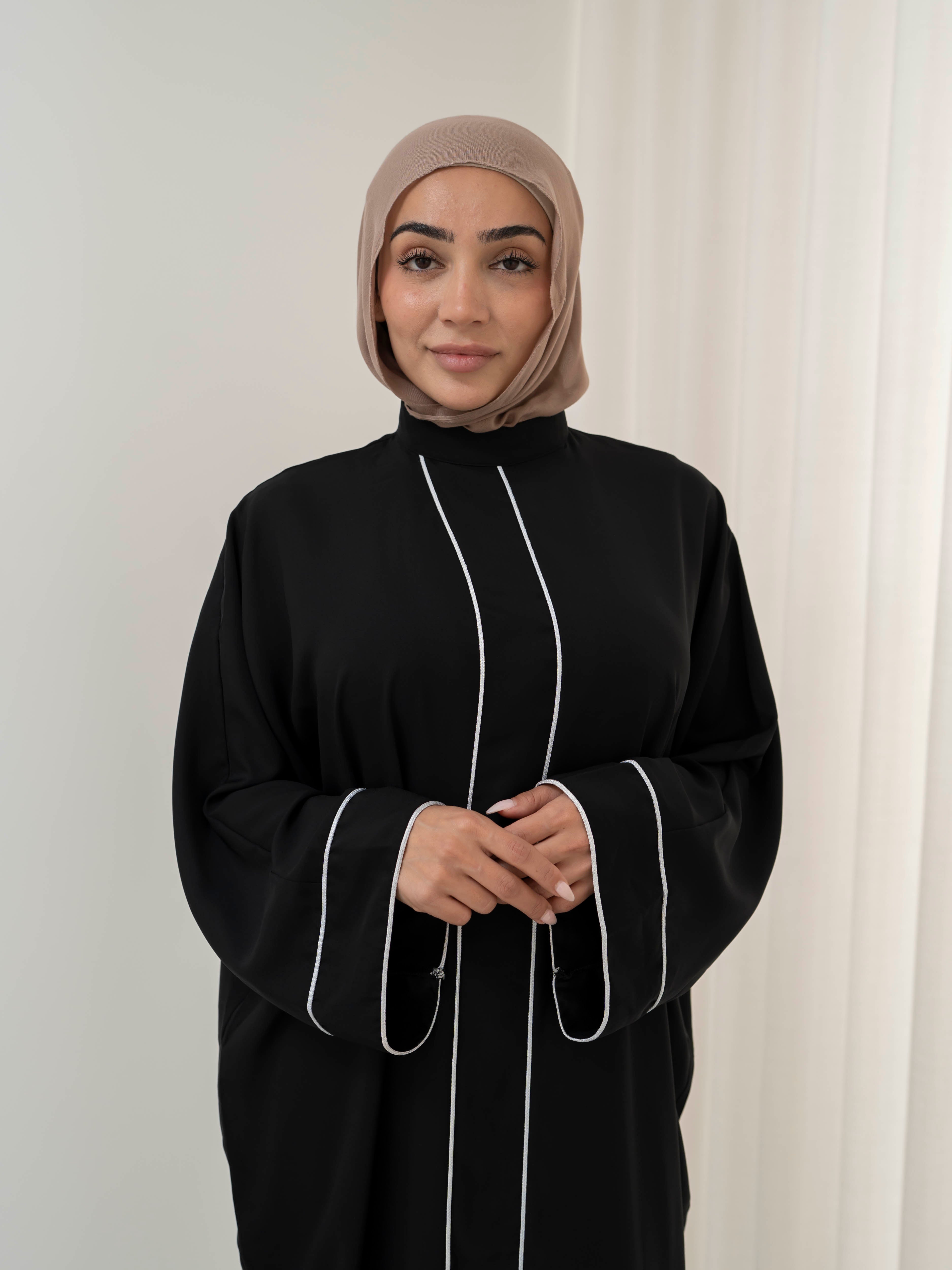 Model wearing the Noor Line abaya featuring a clean silhouette with subtle line detailing, styled for a modest and elegant look suitable for Ramadan and Eid.
