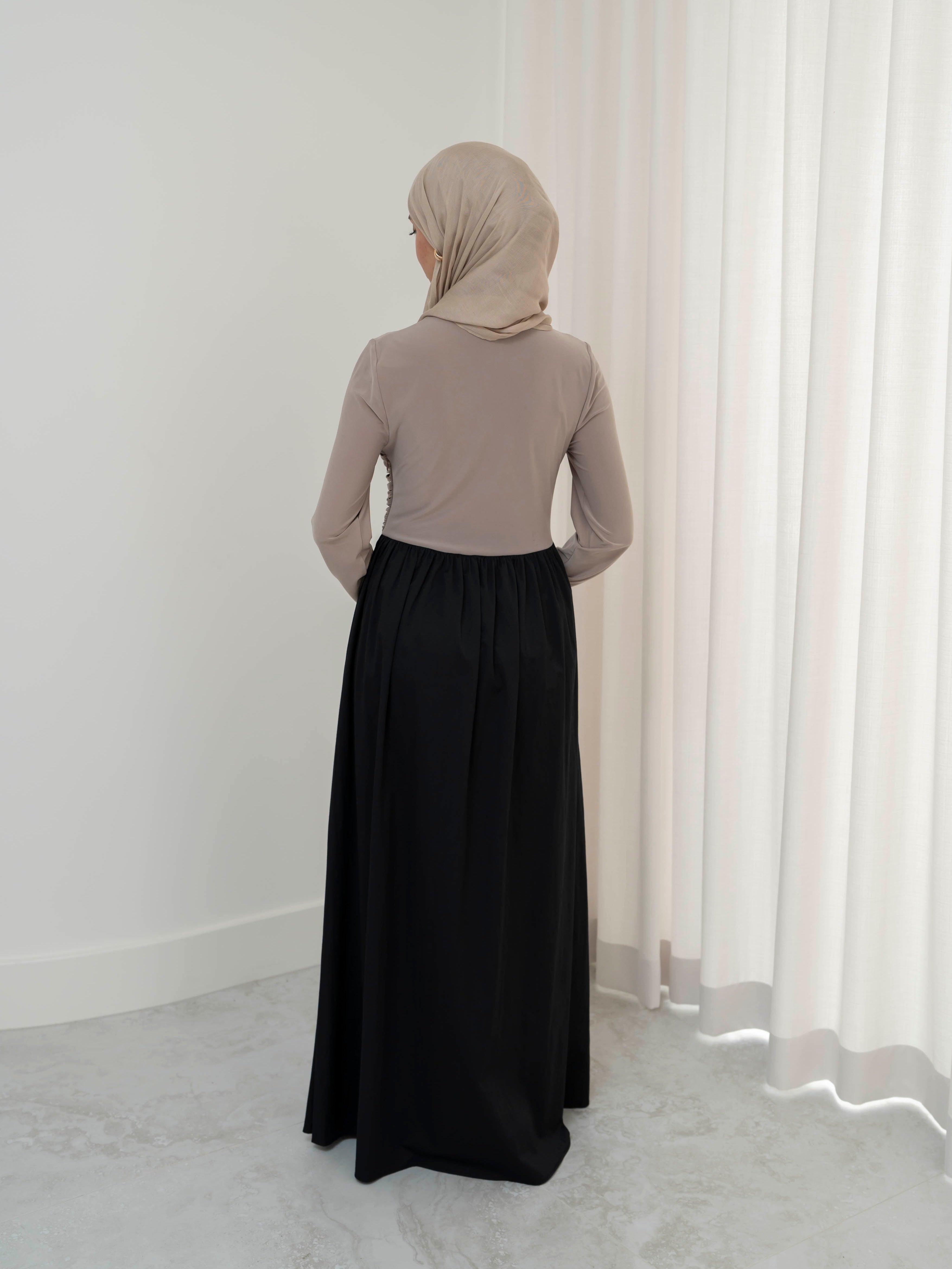 Model wearing the Aicha gathered dress featuring a jersey bodice and poplin skirt with soft gathered detailing, styled for a modest and elegant look suitable for Ramadan and Eid.