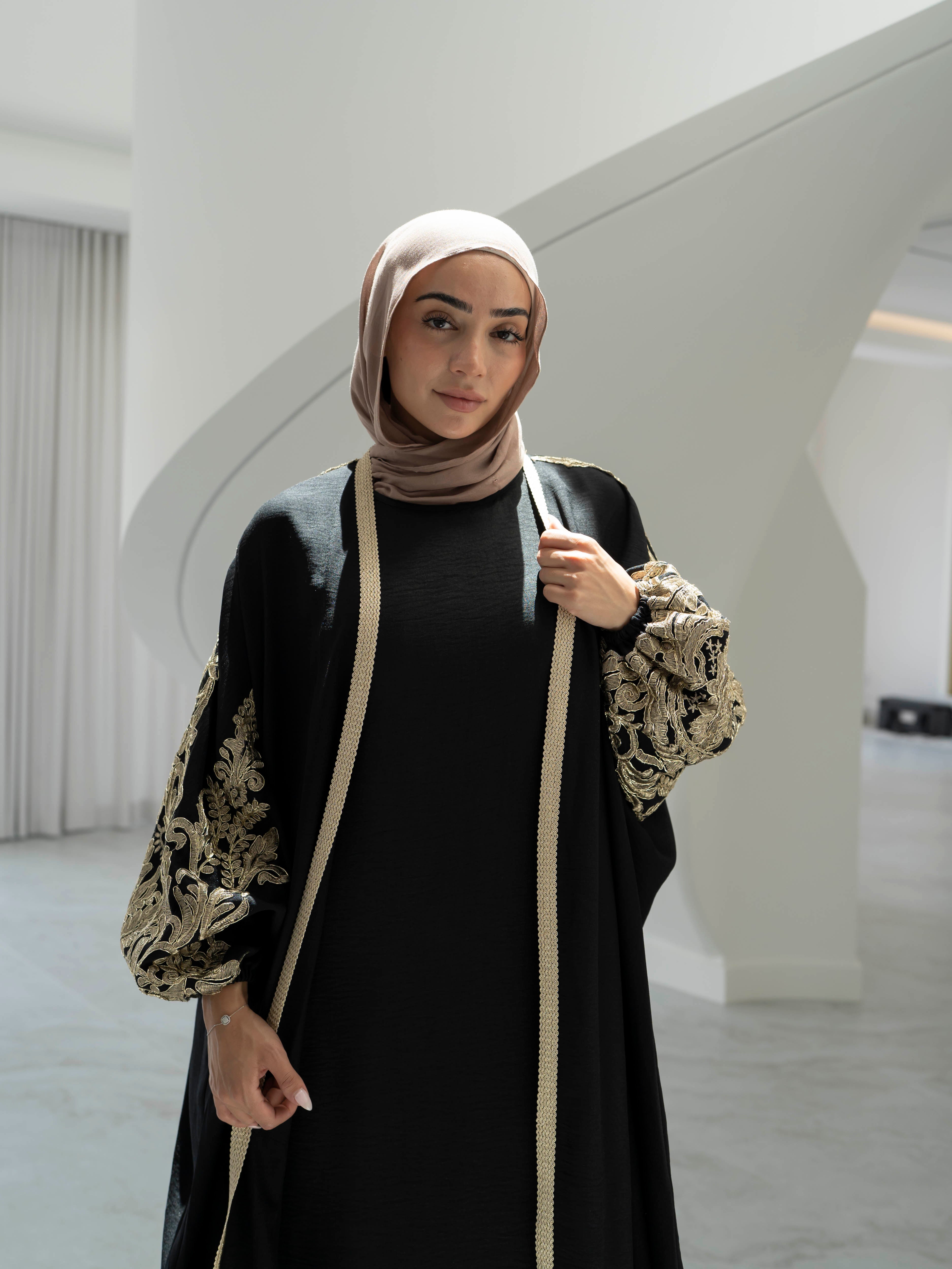 Model wearing the Haya two-piece abaya set featuring a gold-embroidered open abaya layered over an inner dress, styled for a modest and elegant look suitable for Ramadan and Eid.