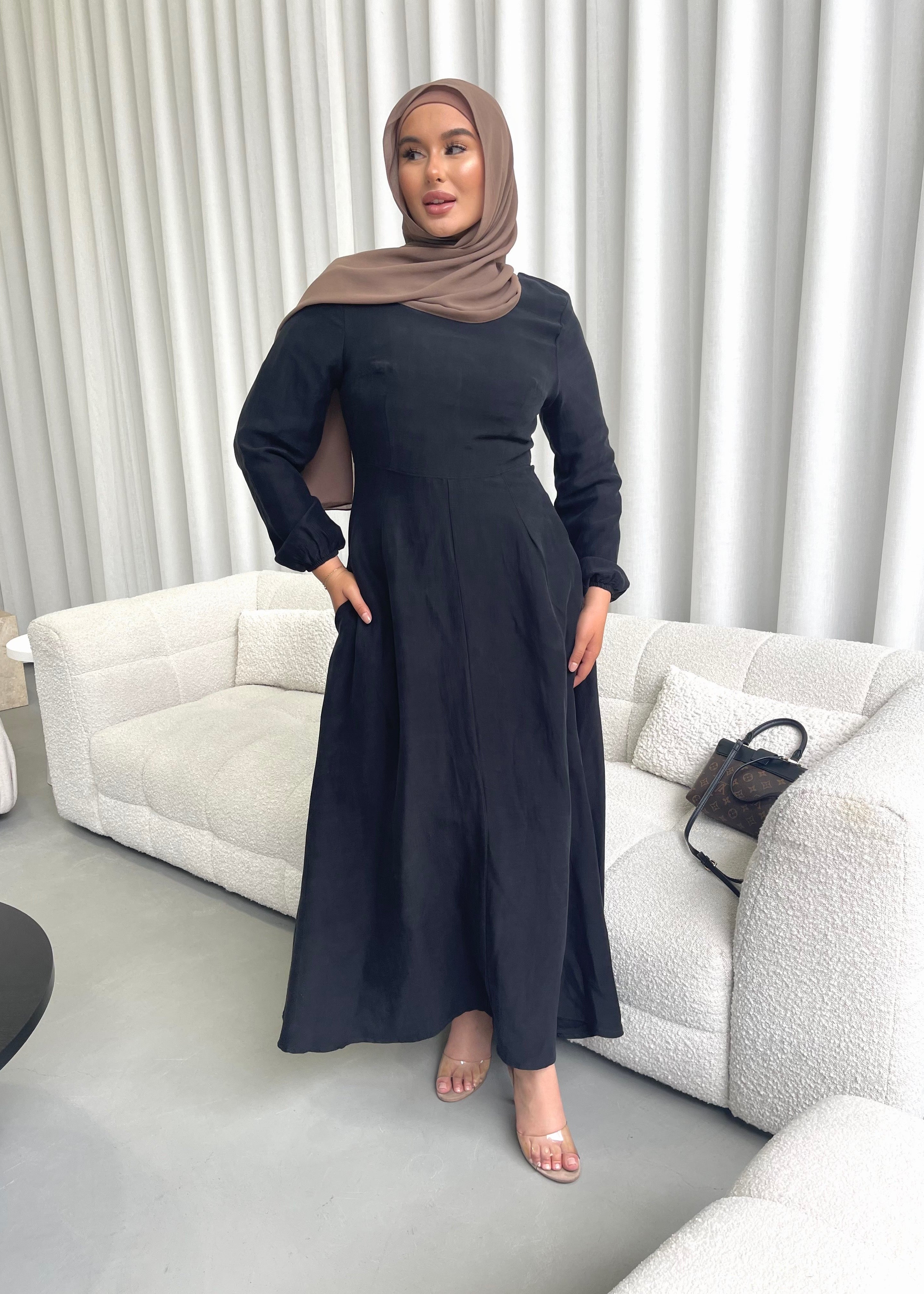 Amira Dress in linen-viscose fabric with long sleeves and a fitted bodice featuring an empire waist and limited stretch. Flows into a loose high-low skirt for an elegant silhouette, suitable for special occasions or styled with heels.