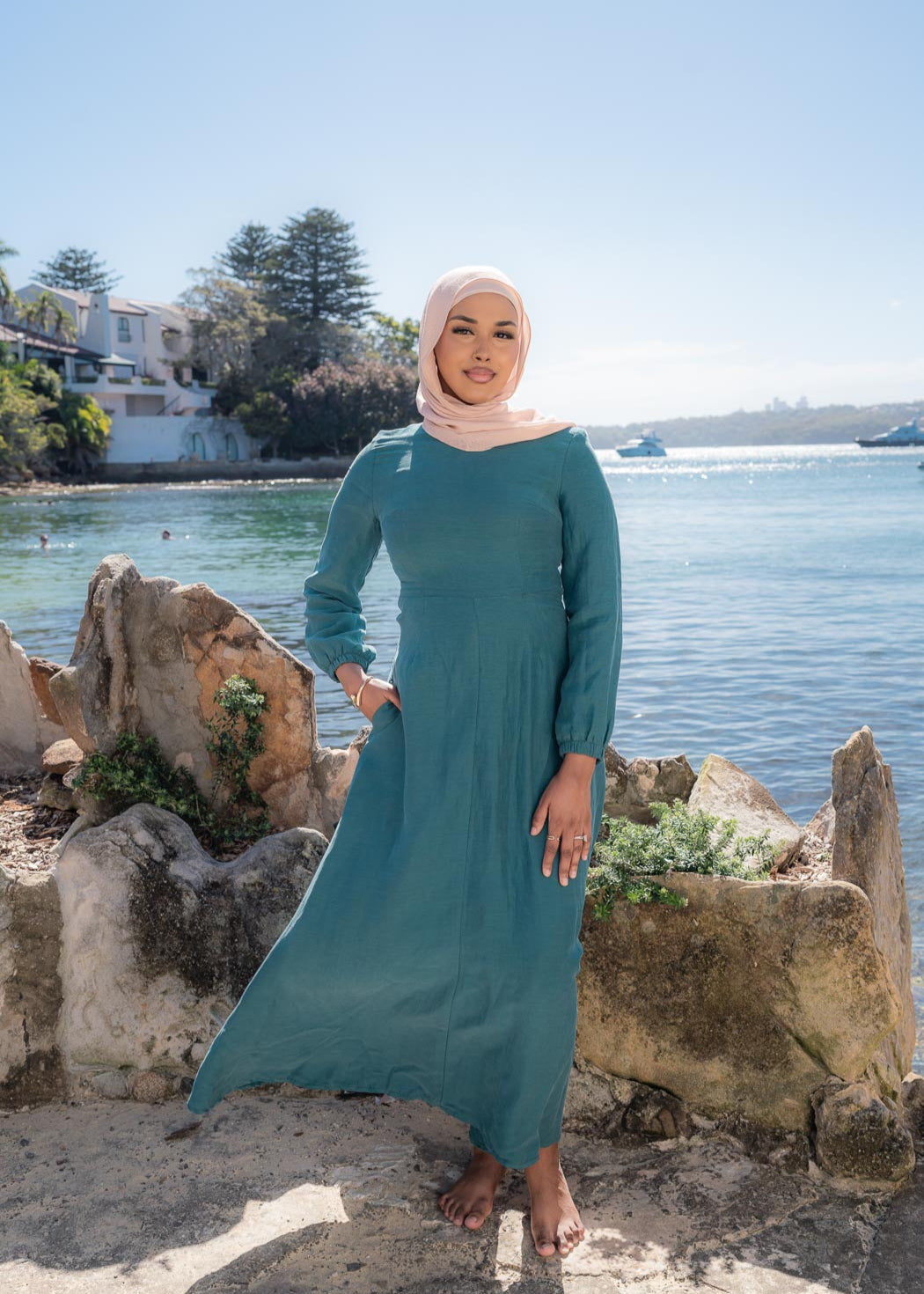 Amira Linen Dress in a soft linen-blend fabric with long sleeves and a fitted bodice featuring limited stretch. Designed with an empire waist that flows into a loose high-low skirt for an elegant, flattering silhouette suitable for special occasions.