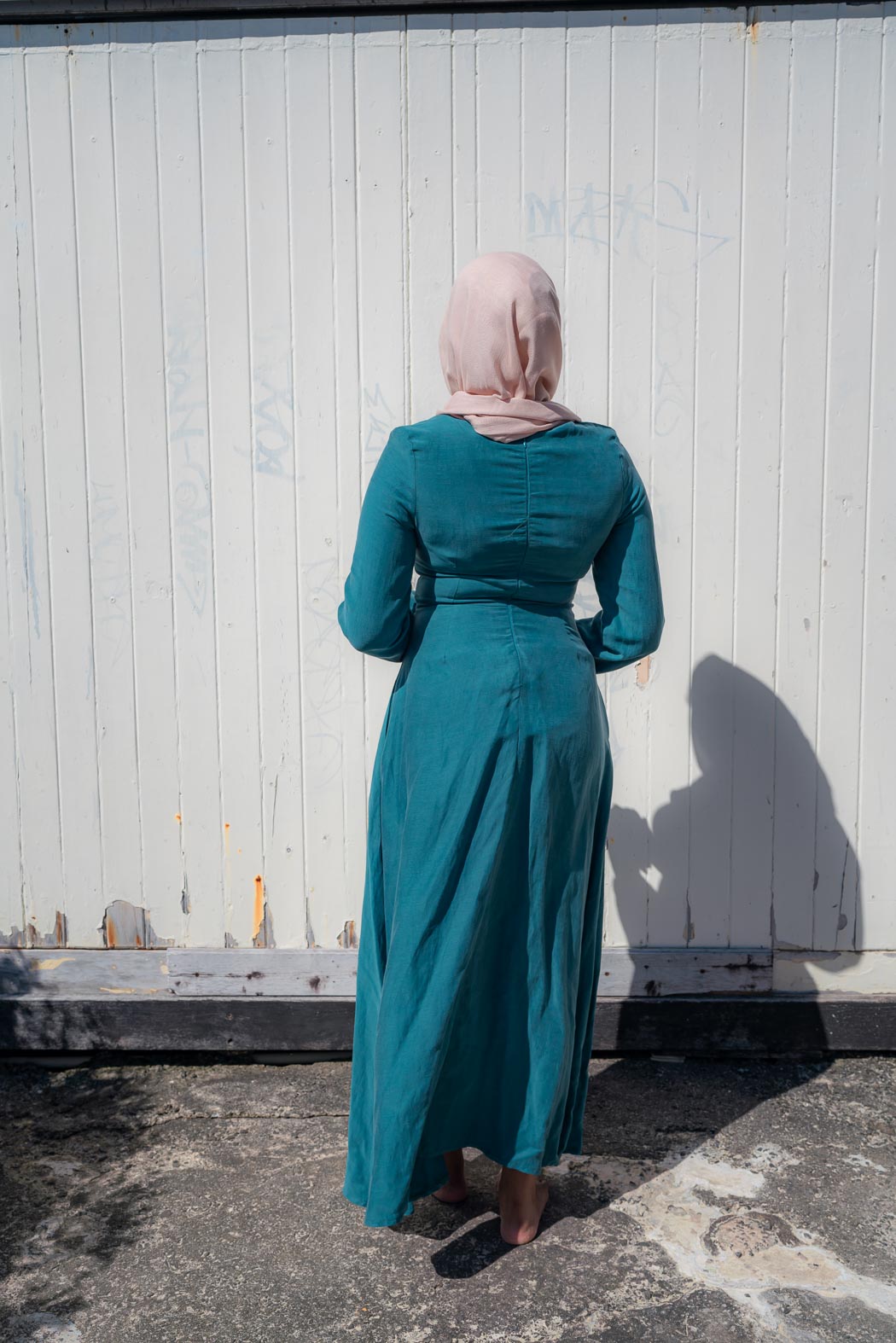 Amira Linen Dress in a soft linen-blend fabric with long sleeves and a fitted bodice featuring limited stretch. Designed with an empire waist that flows into a loose high-low skirt for an elegant, flattering silhouette suitable for special occasions.