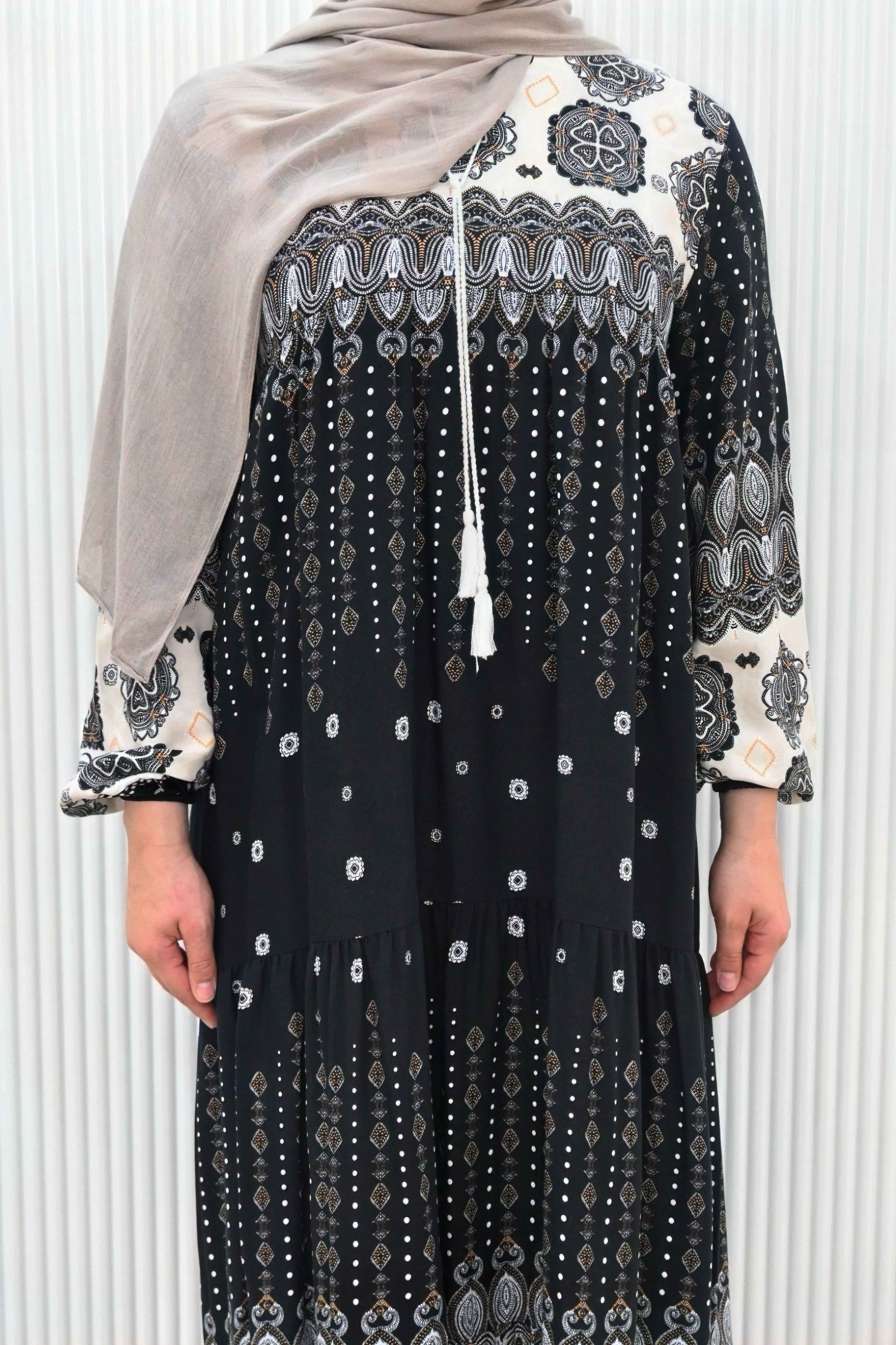 This is a long, loose-fit maxi dress with long sleeves. It features floral and geometric patterns with a flowy gathered design, making it stylish and modest.