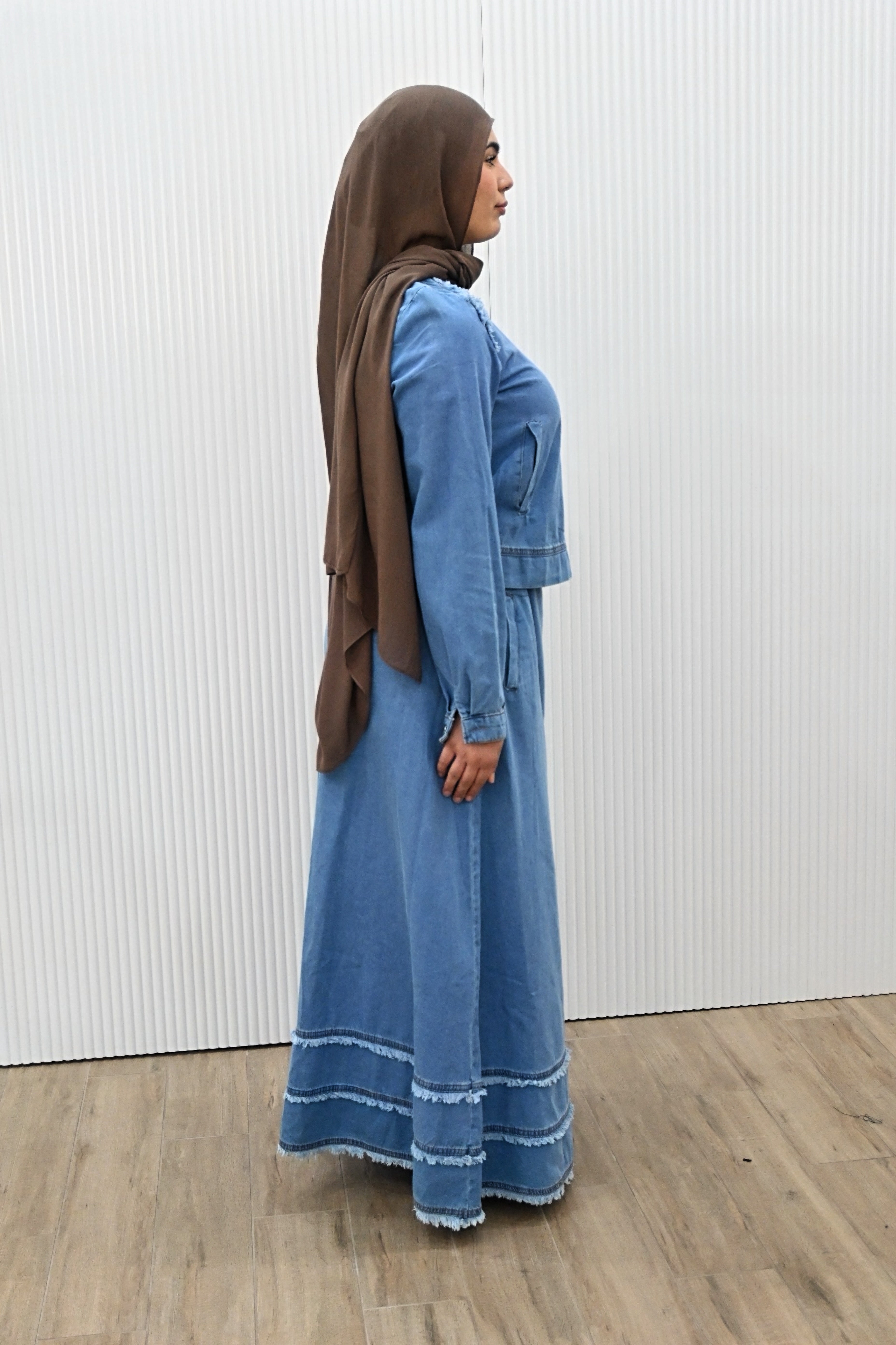 This is a two-piece modest denim-style outfit featuring a long A-line skirt and a matching zip-up jacket. The skirt has layered frayed hem details for a casual chic look, while the jacket is designed with full sleeves and light embroidery accents on the shoulder. Paired with a plain inner top, this set combines comfort and style, making it perfect for everyday wear or casual outings.