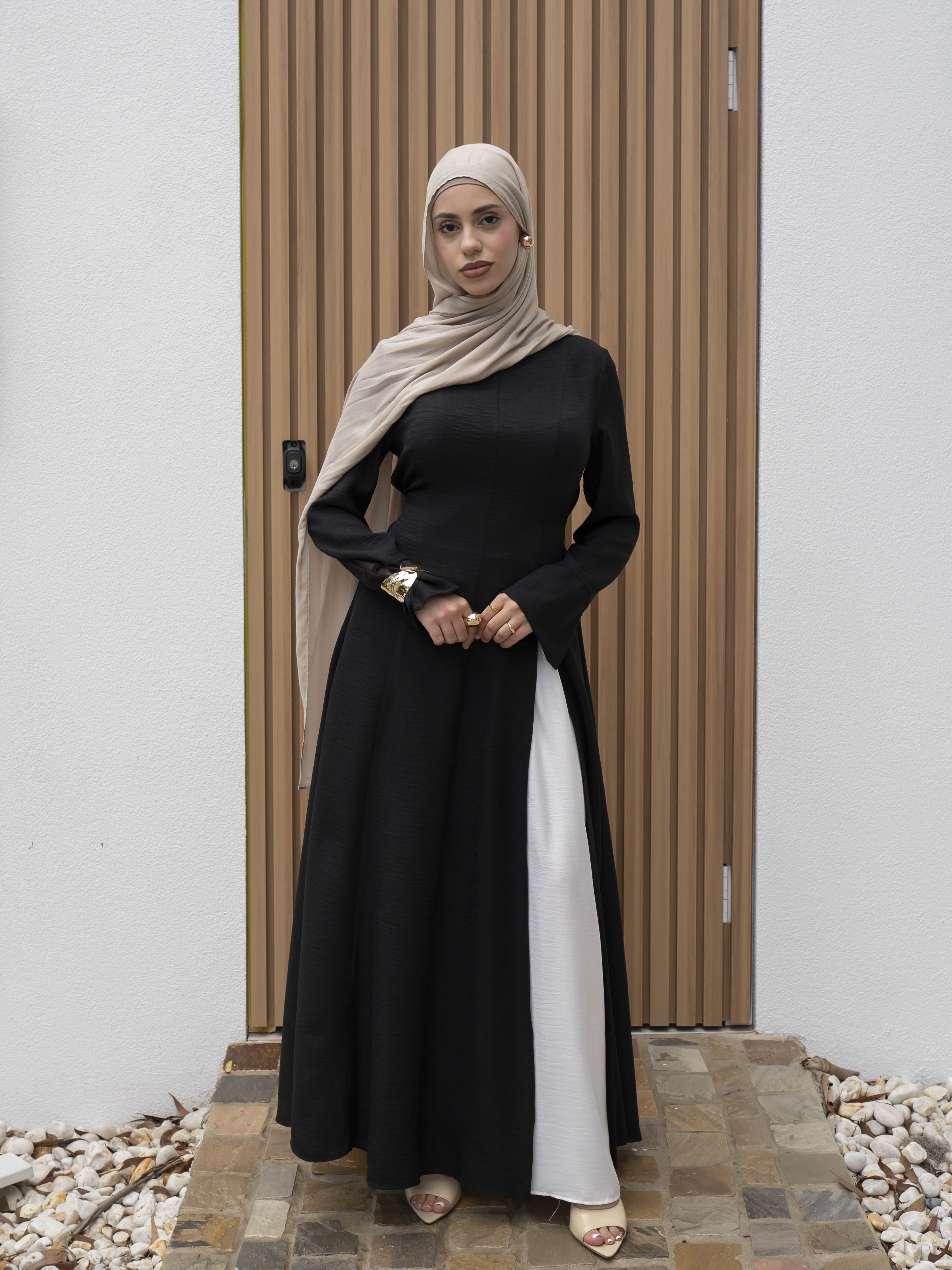 Isla Panelled Dress Set, a two-piece outfit with a tailored outer dress and contrasting inner skirt in a structured, full-length design. Features long sleeves with cuffs, an adjustable waist tie, and lightweight fabric with elegant drape, offering a modest and polished look for formal occasions or Eid.