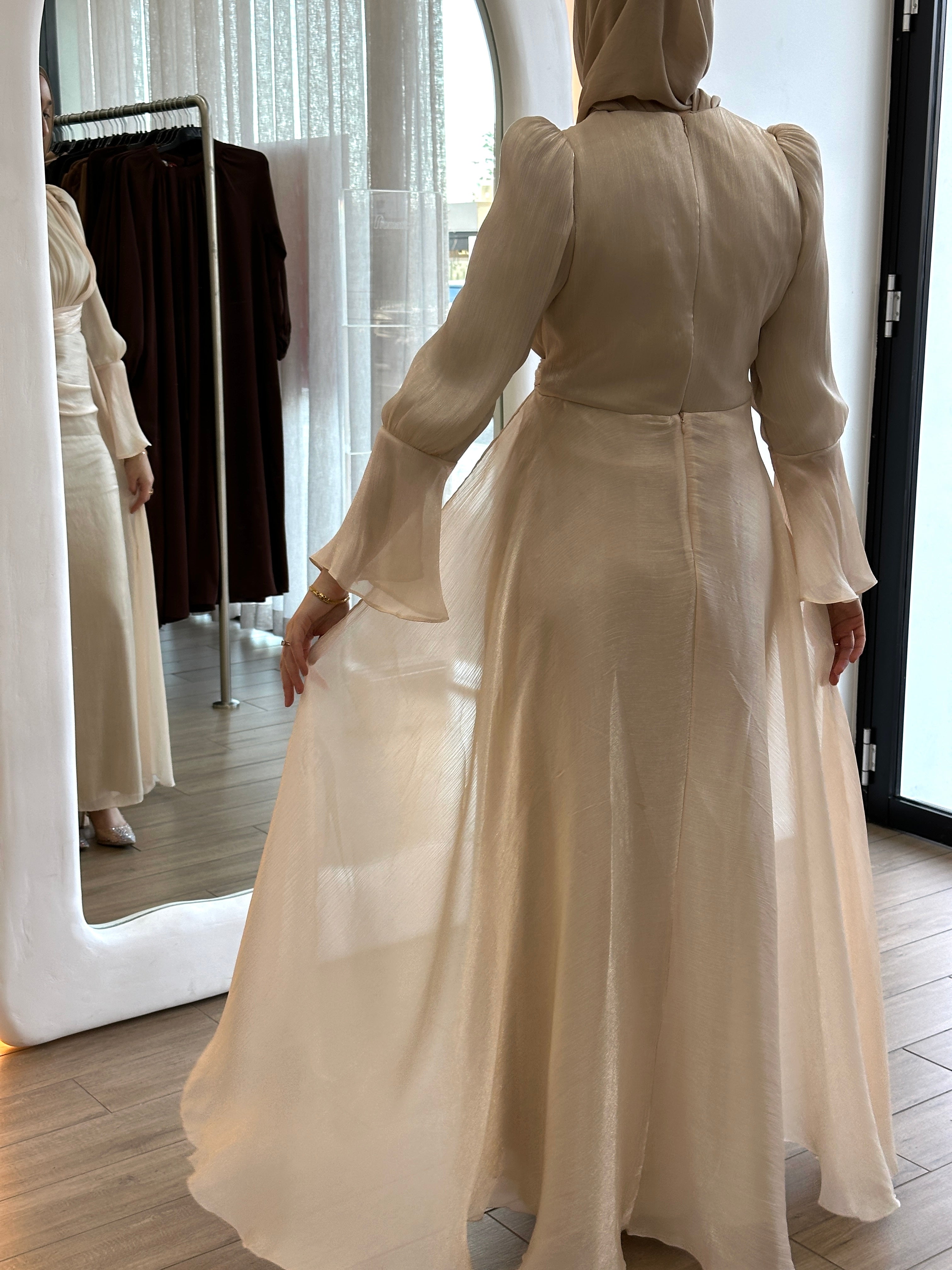 Lamis Formal Dress in shimmery chiffon featuring a ruched bodice with delicate pleat seams and an A-line skirt with flowing drape panels. Designed with long sleeves, fluted cuffs, a ruffled floor-length hem, invisible back zip, and full lining — perfect for elegant formal occasions.