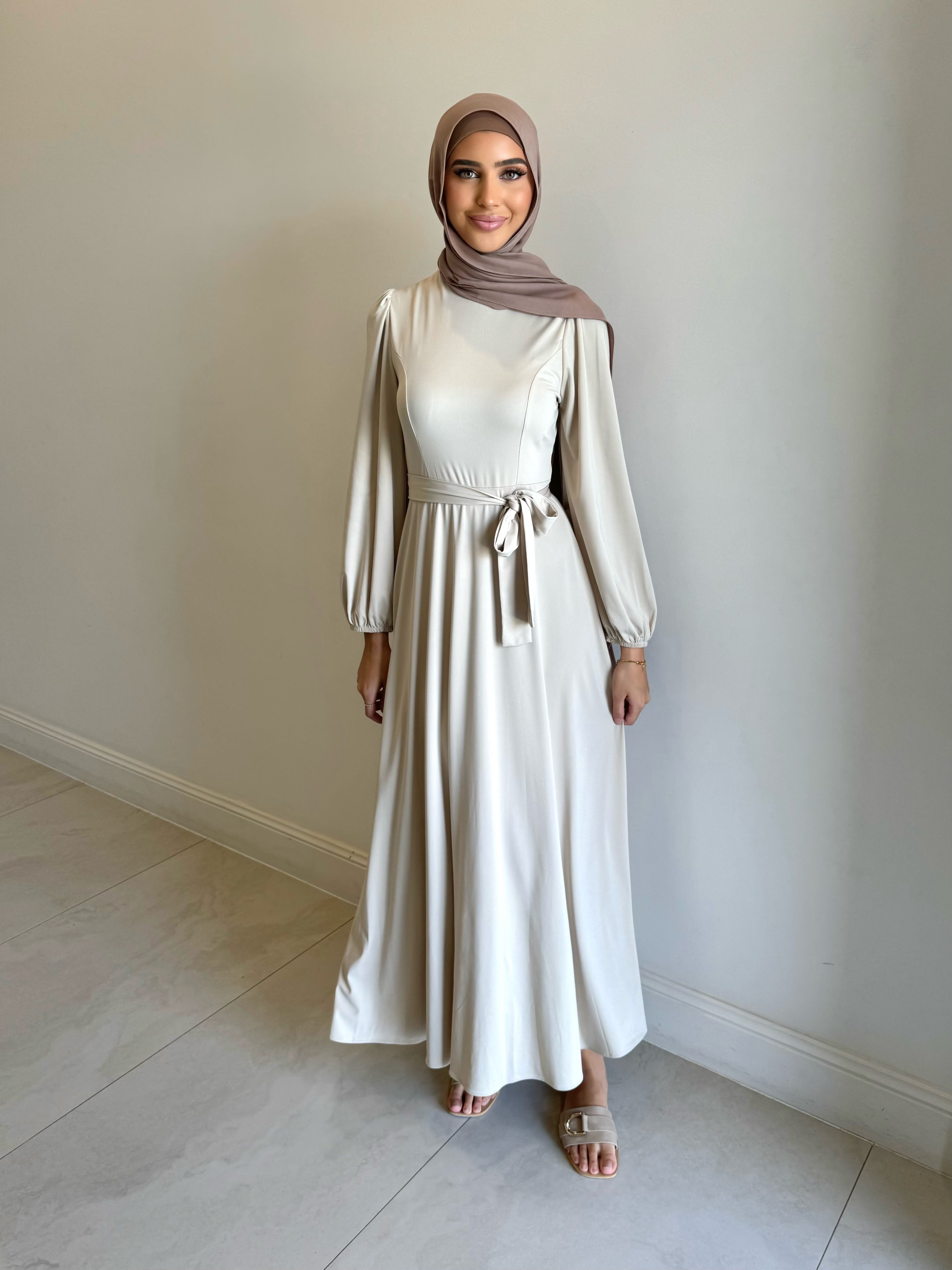 It has long sleeves and a fitted bodice with limited stretch, then drops from an empire cut waist to a loose high low skirt.