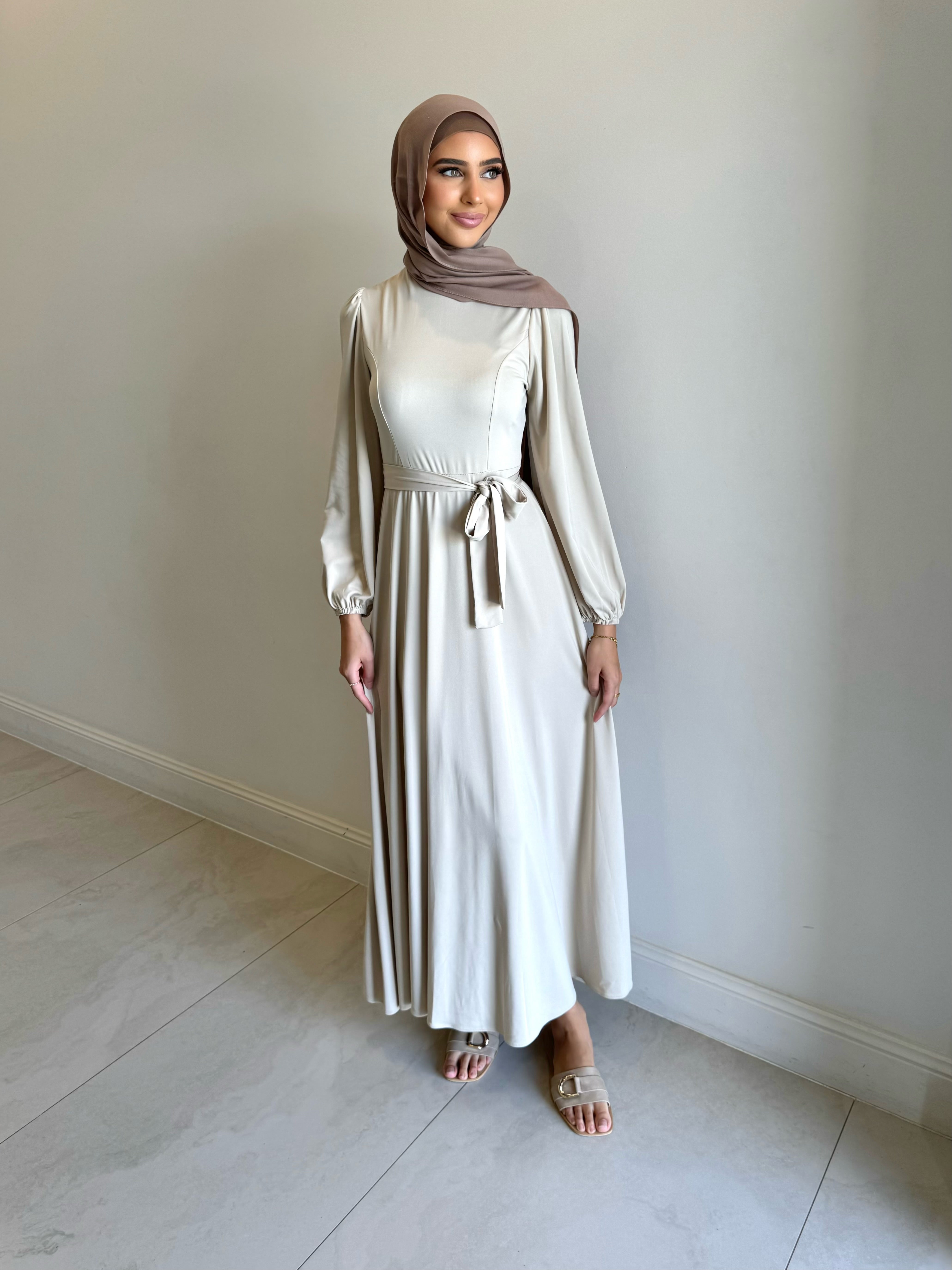 It has long sleeves and a fitted bodice with limited stretch, then drops from an empire cut waist to a loose high low skirt.