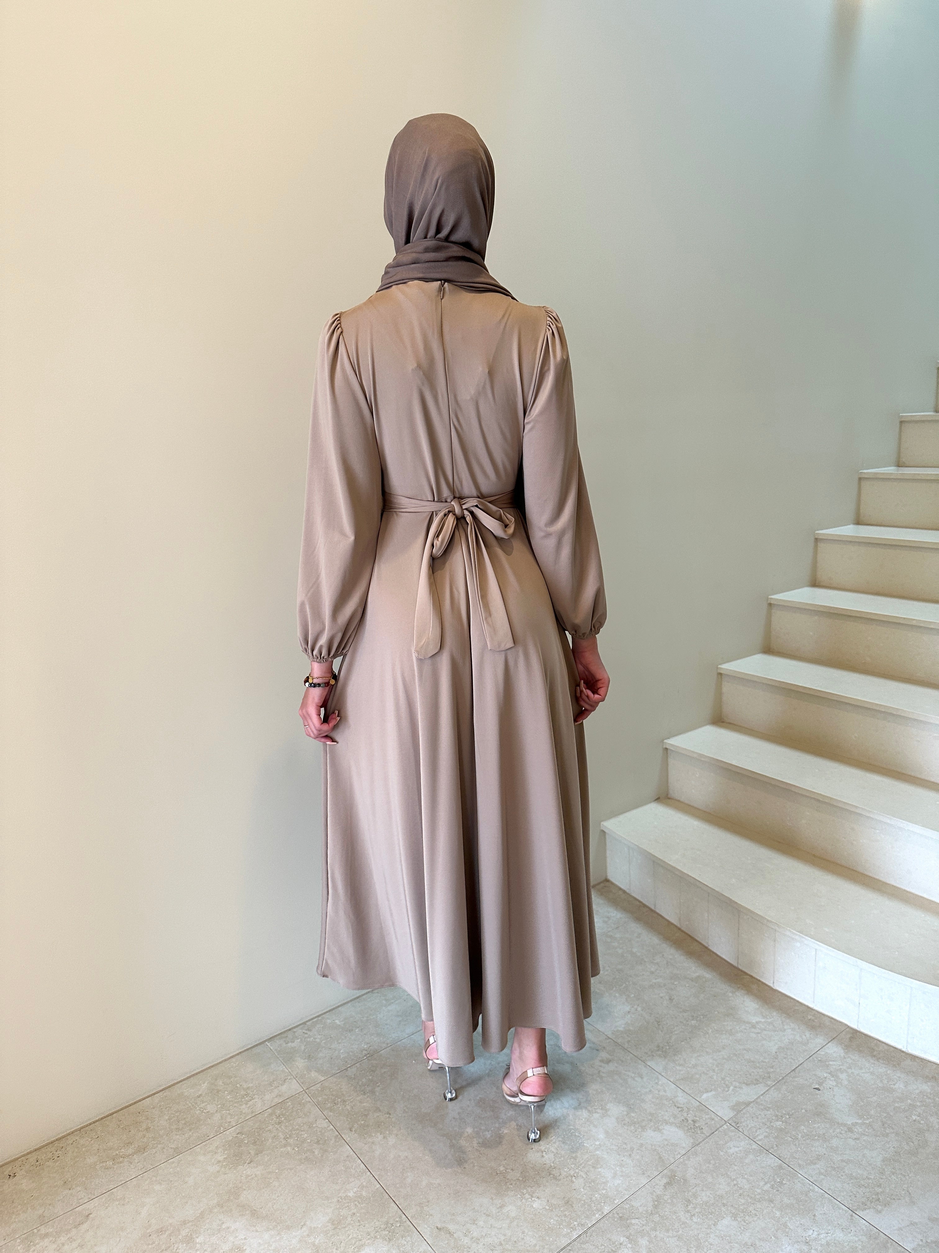 It has long sleeves and a fitted bodice with limited stretch, then drops from an empire cut waist to a loose high low skirt.