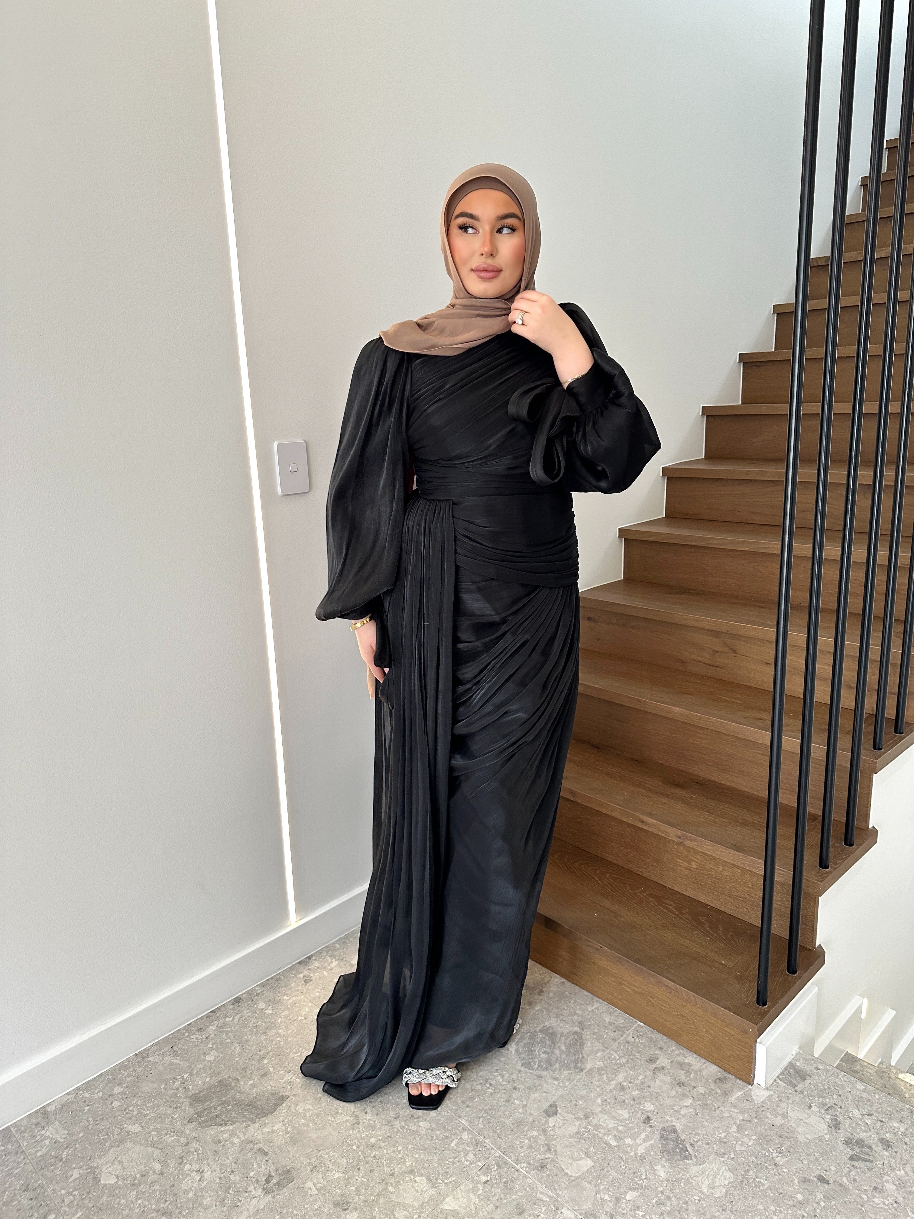 Layan Formal Dress in shiny organza with all-over ruching, fitted waist, and cascading floor-length panel. Features statement balloon sleeves with ribbon tie cuffs and full lining — perfect for elegant formal occasions.