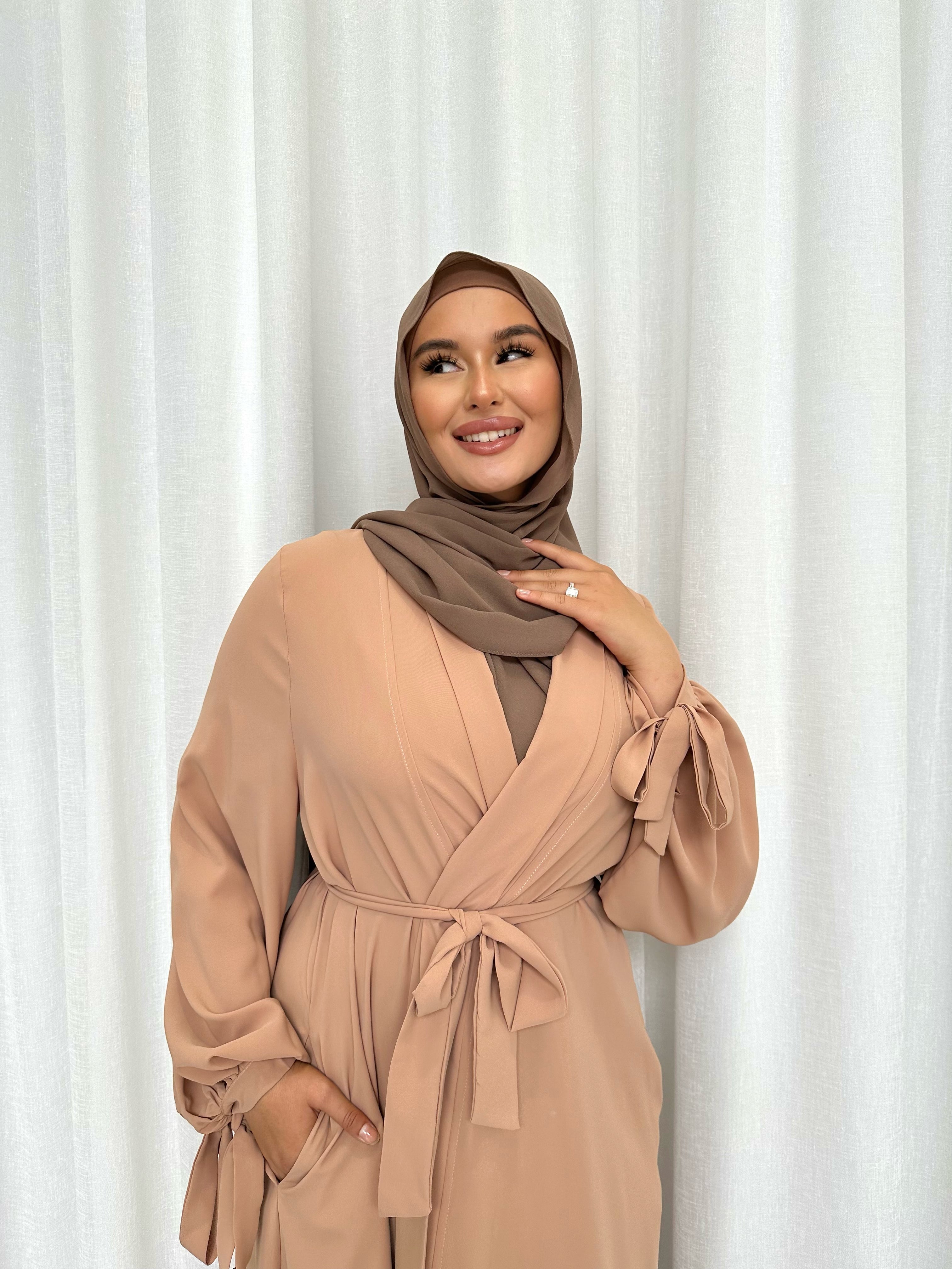 It's made from polyester, designed for a loose fit on the body and has long balloon sleeves with shirred tie cuffs then drops to a floor length.