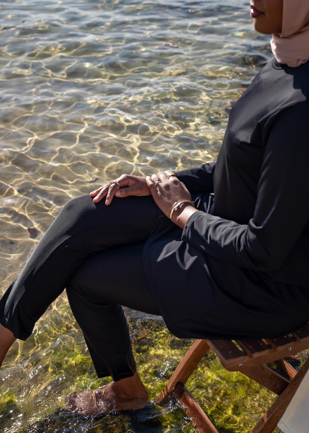 Model wearing the Marina modest swimwear set in black or mauve, featuring a long-sleeve top that falls above the knee and loose trousers with an elasticated waistband. Made from stretch scuba fabric (85% polyester, 15% elastane) for a comfortable fit.