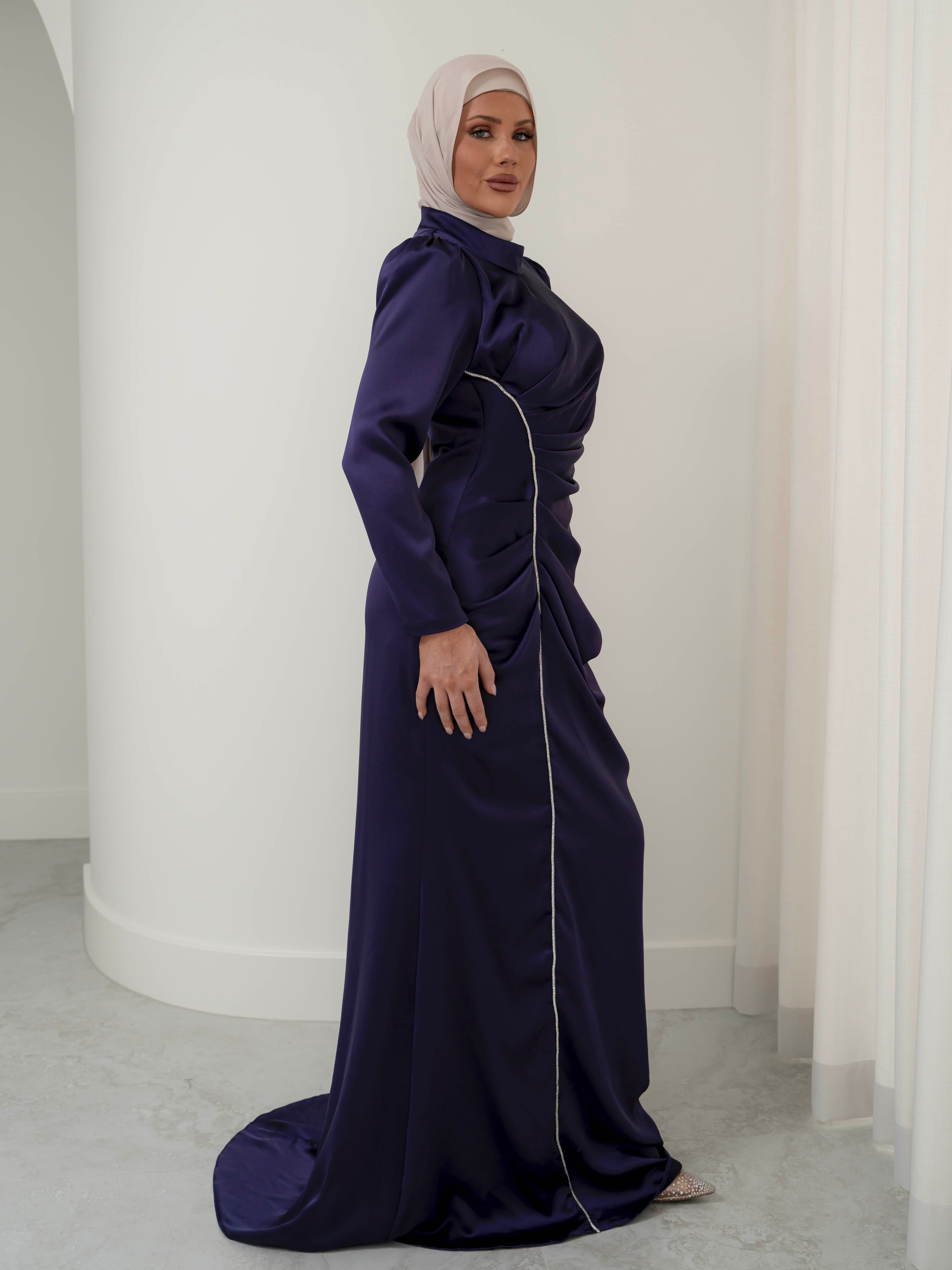 Elevate your formal look with the OLA FORMAL DRESS- INDIGO. Crafted from a shiny satin crepe fabric, this dress boasts elegant asymmetric gathers and a flattering silhouette that will make you stand out. Complete with long slim sleeves and a floor-skimming hem, this dress is perfect for any formal occasion.