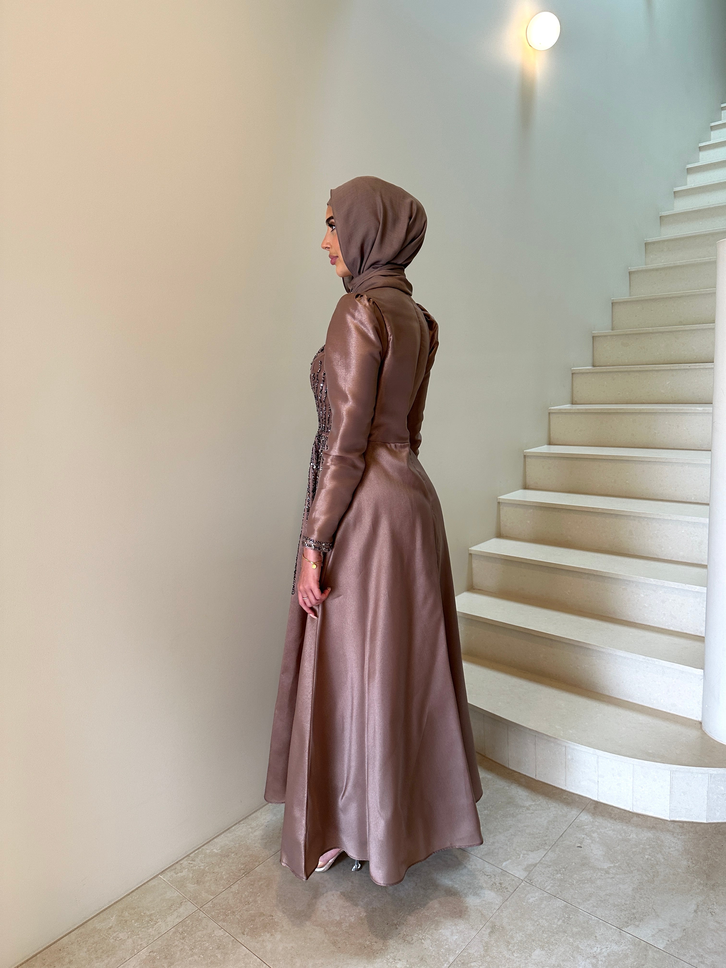Shaima Formal Dress in shiny satin with a fitted waist and ball gown skirt. Features high neck, puffy shoulders, long sleeves, and sequined embellishments on bodice and skirt with an invisible back zip — perfect for formal occasions.