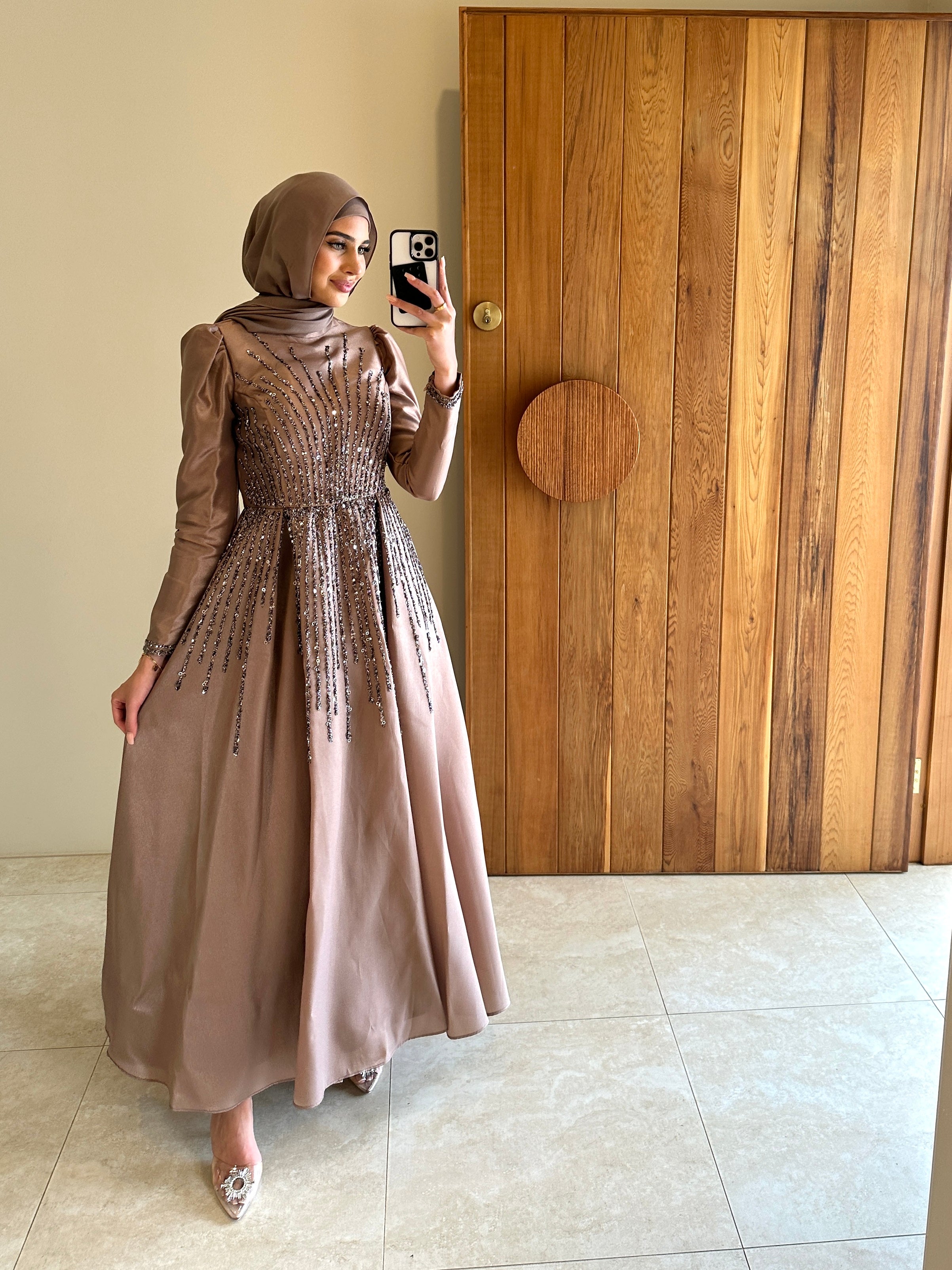 Shaima Formal Dress in shiny satin with a fitted waist and ball gown skirt. Features high neck, puffy shoulders, long sleeves, and sequined embellishments on bodice and skirt with an invisible back zip — perfect for formal occasions.