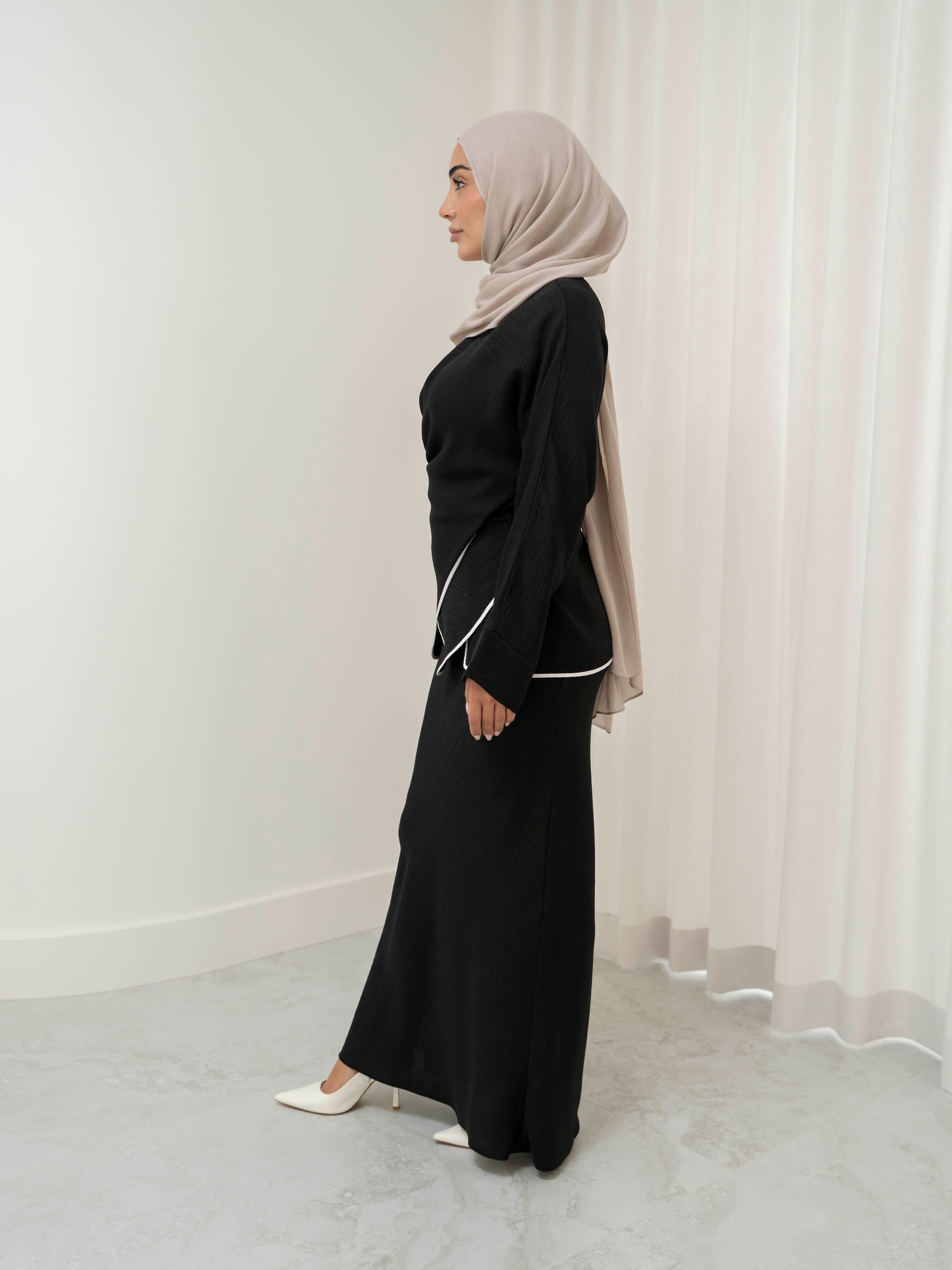 Sienna Wrap Set, a two-piece outfit with a wrap-style tie top featuring contrast piping and long sleeves, paired with a full-length flowing skirt. Lightweight fabric drapes elegantly for a modest, refined silhouette suitable for Eid, special occasions, or versatile everyday wear.