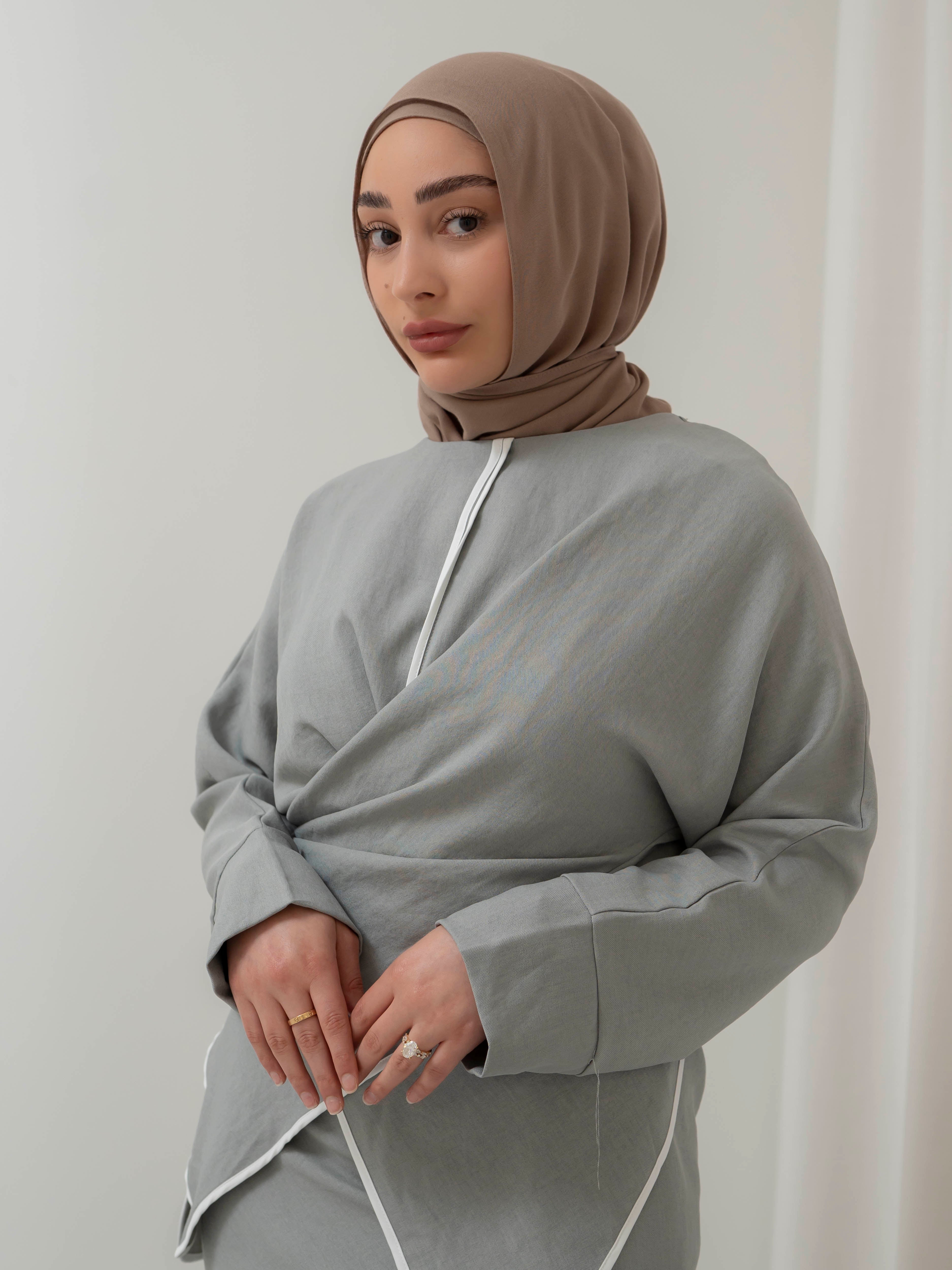Sienna Wrap Set, a two-piece outfit with a wrap-style tie top featuring contrast piping and long sleeves, paired with a full-length flowing skirt. Lightweight fabric drapes elegantly for a modest, refined silhouette suitable for Eid, special occasions, or versatile everyday wear.