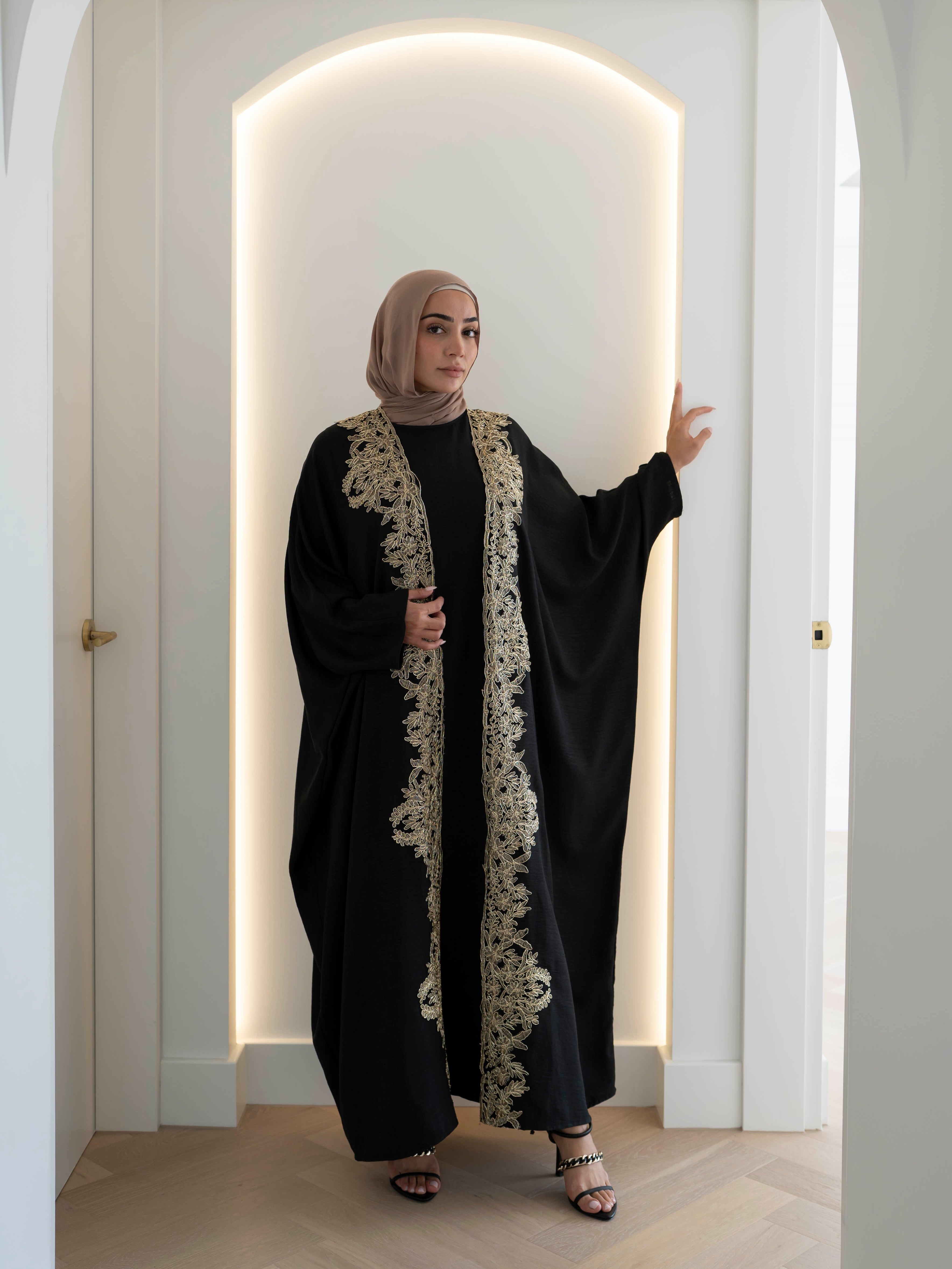 Sultanah Abaya with flowing silhouette and intricate gold embroidery, designed for elegant, modest formal wear. Features delicate gold detailing for a refined, regal finish and includes a sleeveless inner dress for comfortable layering. Perfect for Eid, special occasions, and formal gatherings.