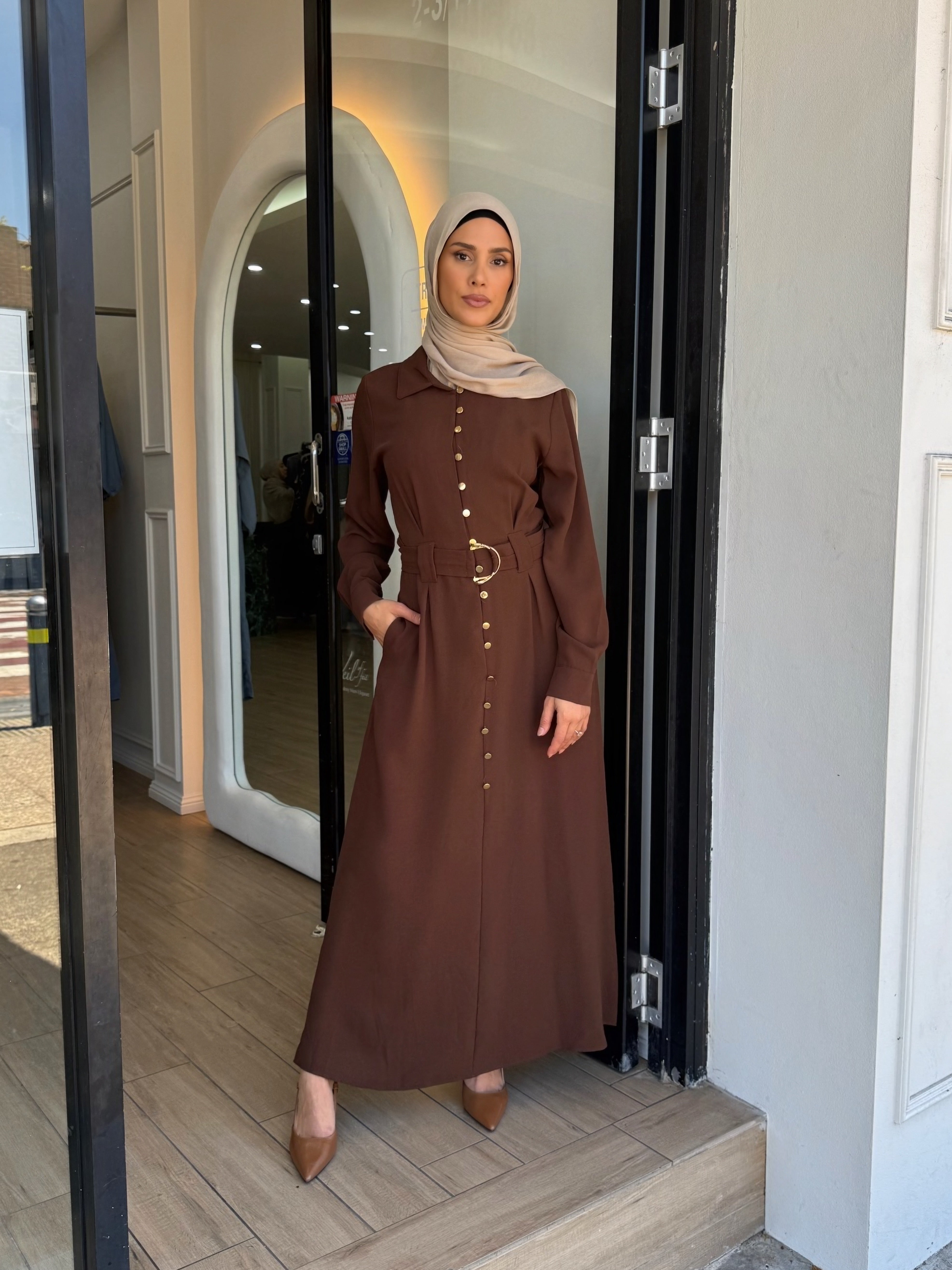 Crafted from a lightweight crepe blend, it features gold-tone buttons, cuffed sleeves, and a removable waist belt that cinches the silhouette beautifully.