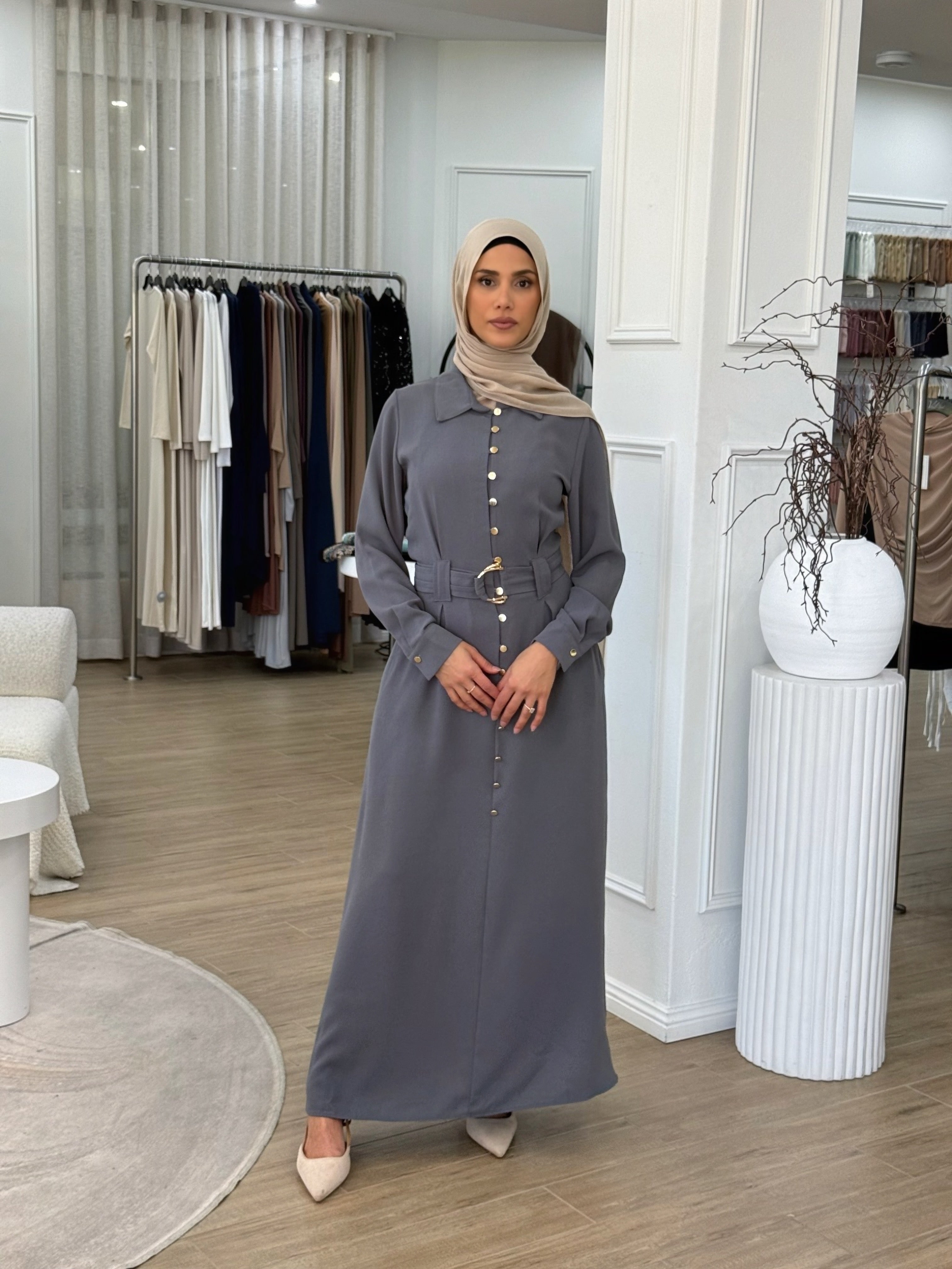 Crafted from a lightweight crepe blend, it features gold-tone buttons, cuffed sleeves, and a removable waist belt that cinches the silhouette beautifully.