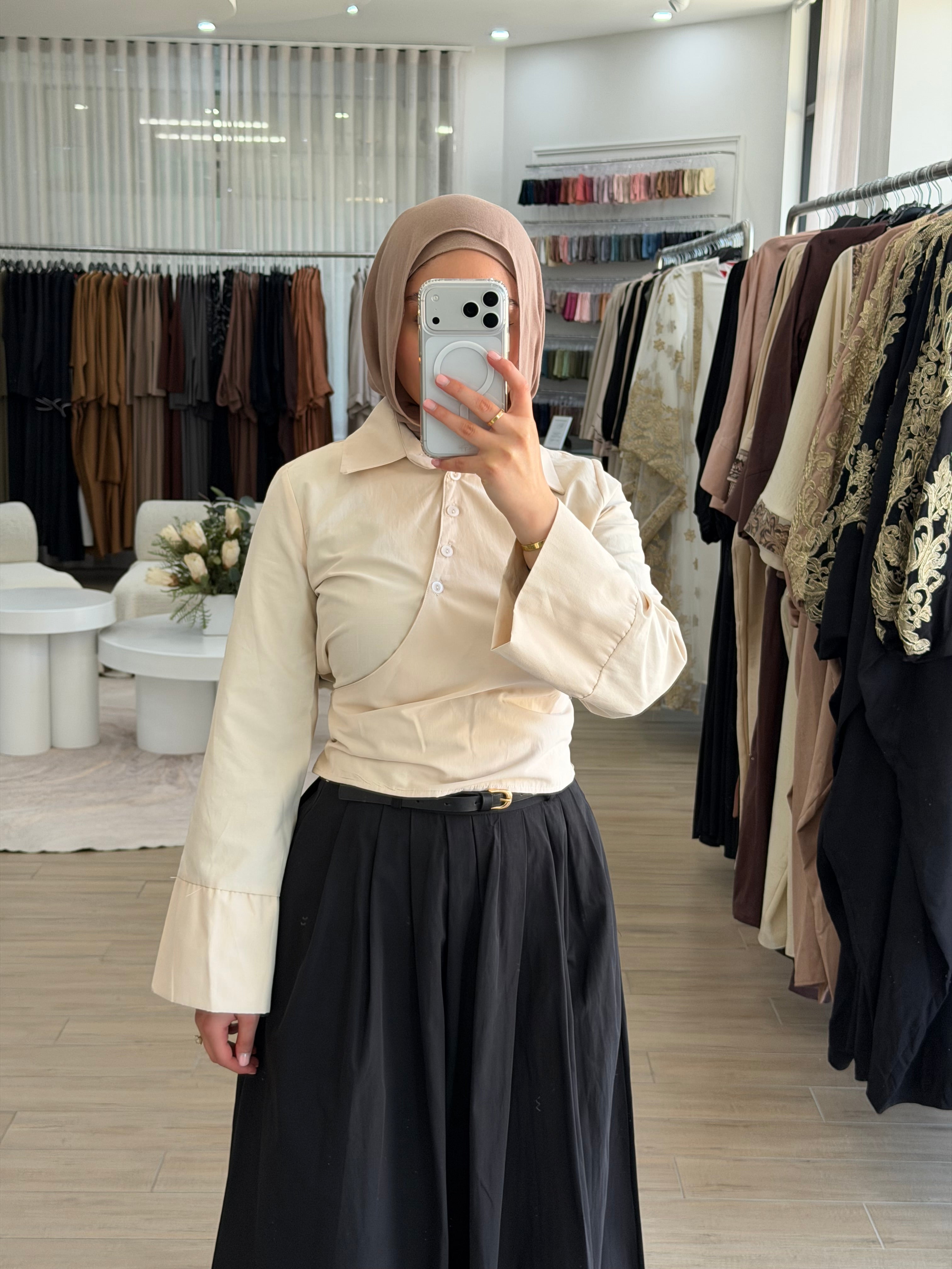 Woman wearing a Manal wrap shirt with a button-down front, asymmetric wrap panel, and cropped hem.