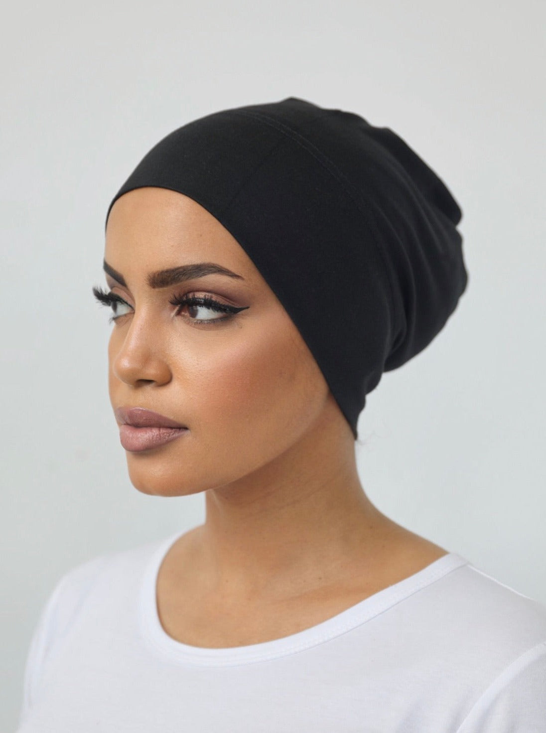 Model wearing a closed under-scarf cap (Veil of Faith) designed to cover hair under a scarf, made from soft natural fibres with a cotton-spandex blend for a comfortable, non-slip fit suitable for all-day wear.