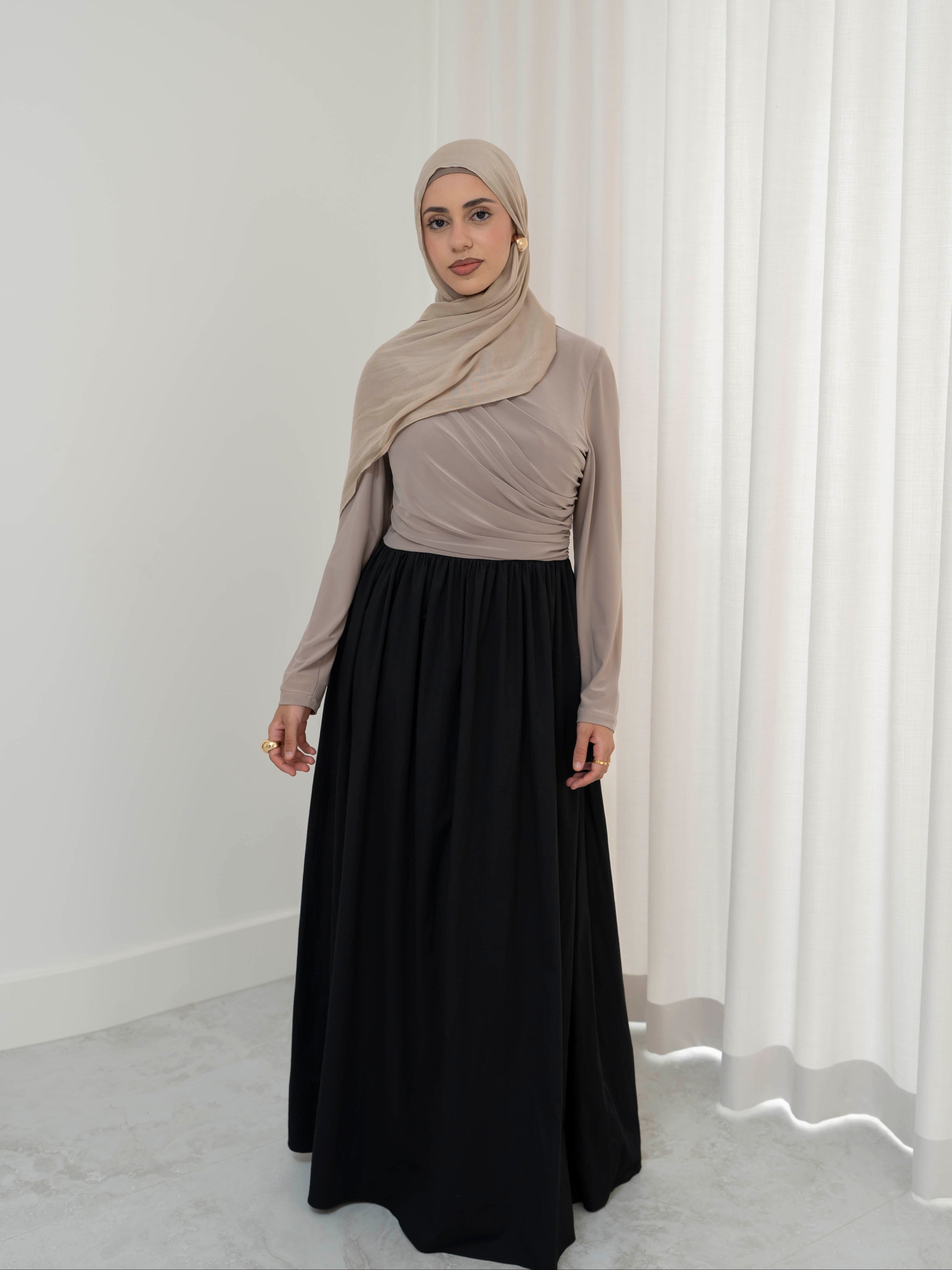 Model wearing the Aicha gathered dress featuring a jersey bodice and poplin skirt with soft gathered detailing, styled for a modest and elegant look suitable for Ramadan and Eid.