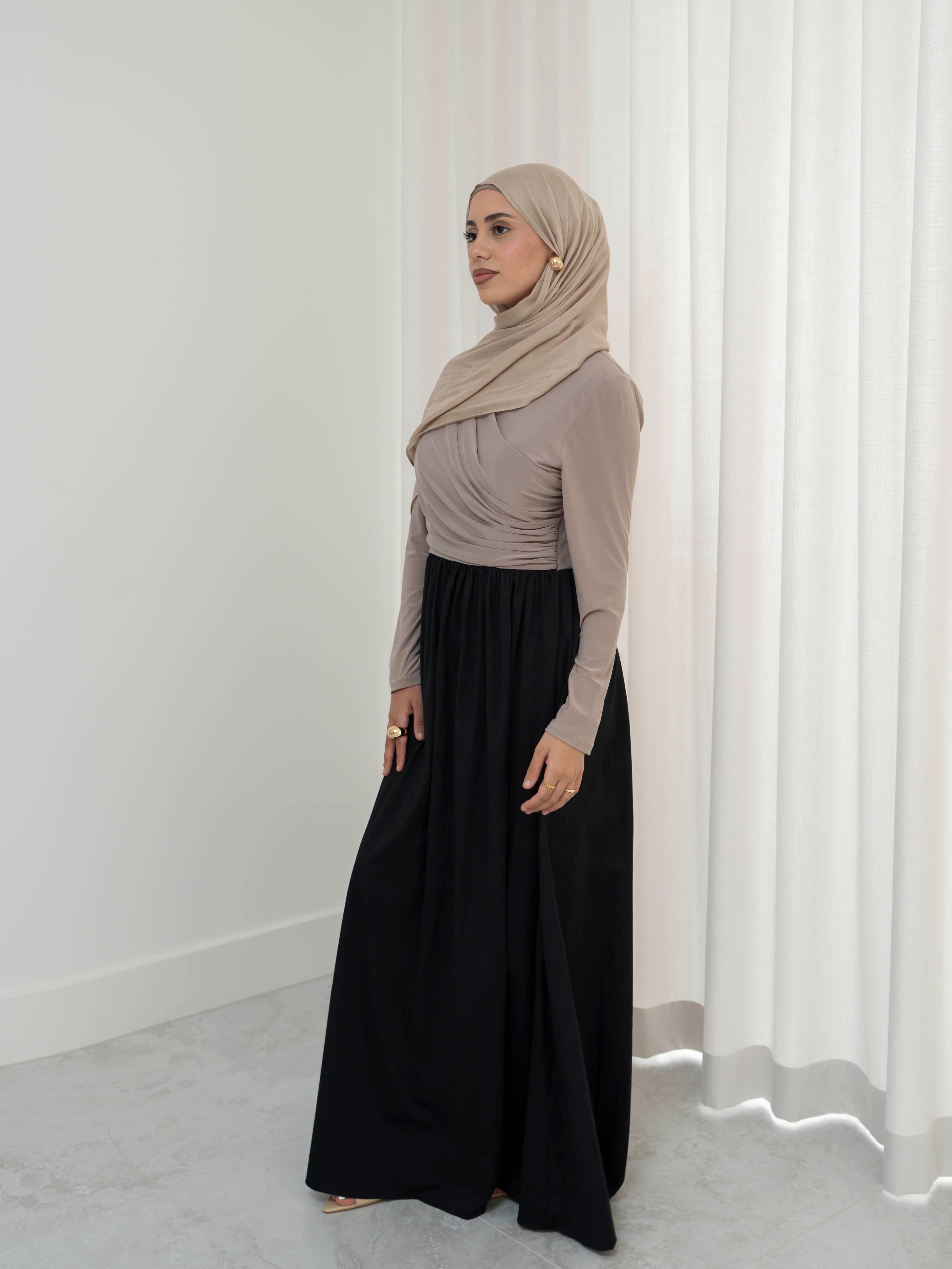 Model wearing the Aicha gathered dress featuring a jersey bodice and poplin skirt with soft gathered detailing, styled for a modest and elegant look suitable for Ramadan and Eid.