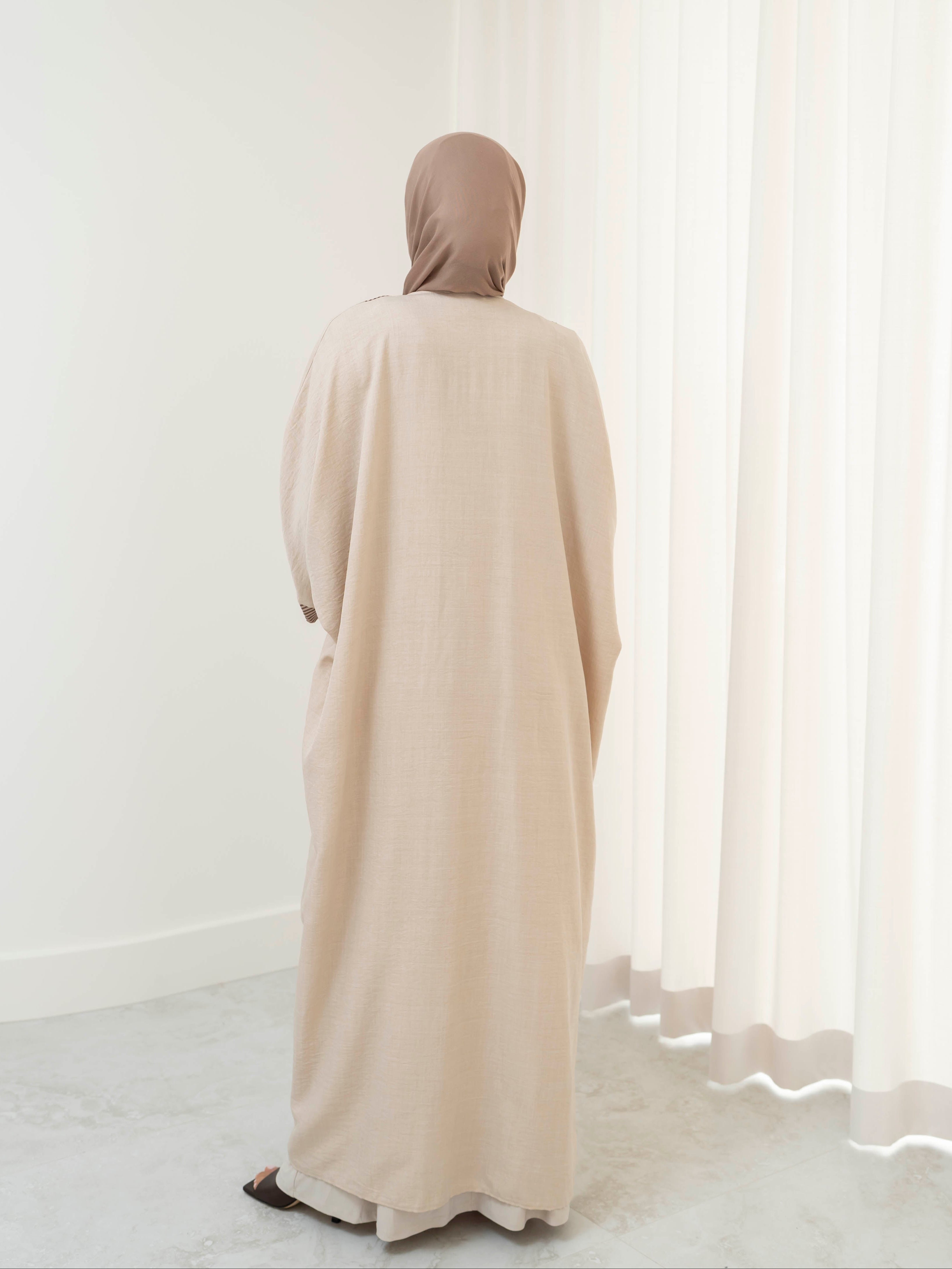 Model wearing the Marwa open abaya featuring a flowing silhouette with fine embellishment detailing, styled open for a modest and elegant look suitable for Ramadan and Eid.