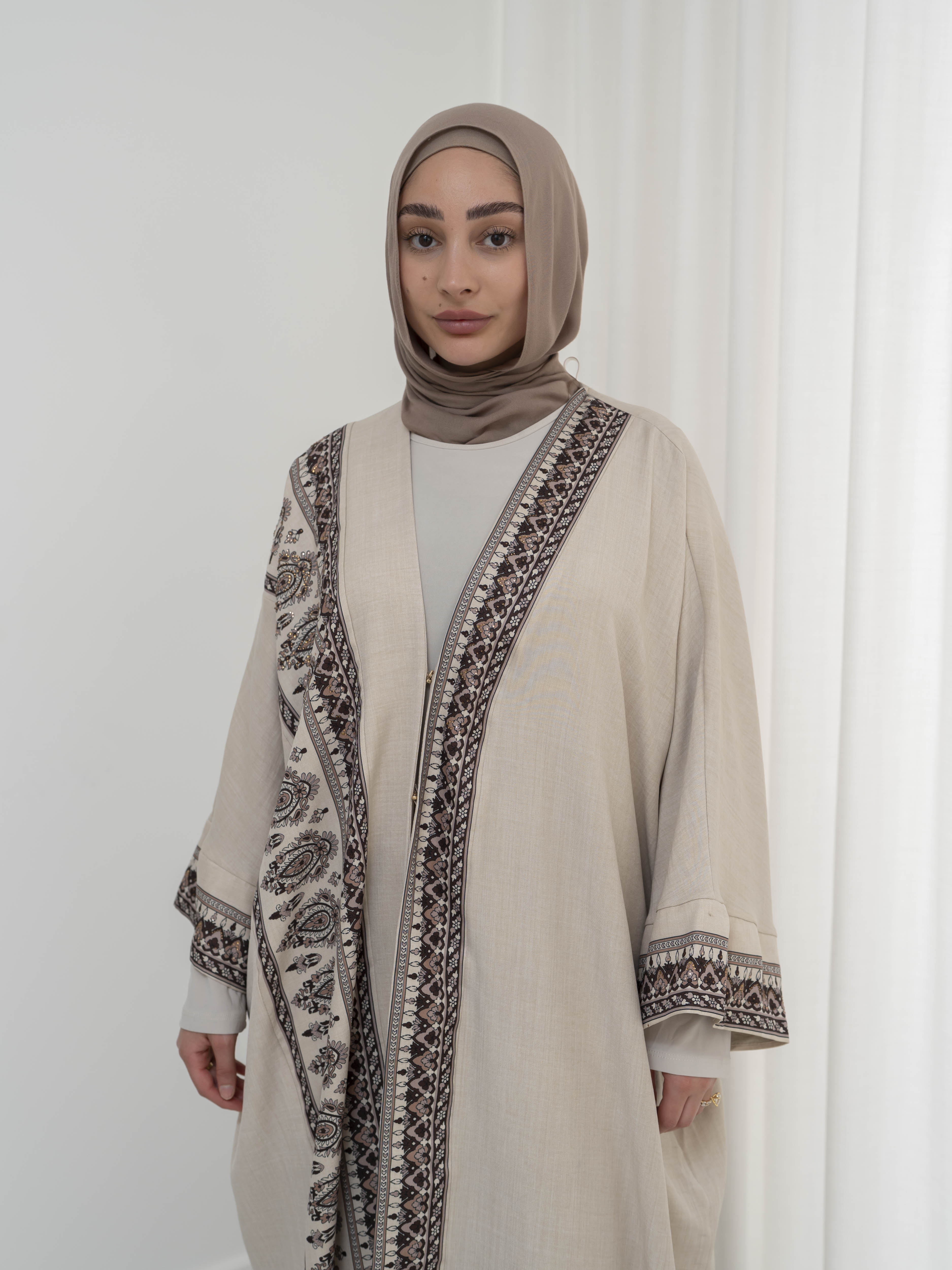 Model wearing the Safiya open abaya featuring a subtle patterned fabric and delicate embellishments, styled open for a modest and elegant look suitable for Ramadan and Eid occasions.