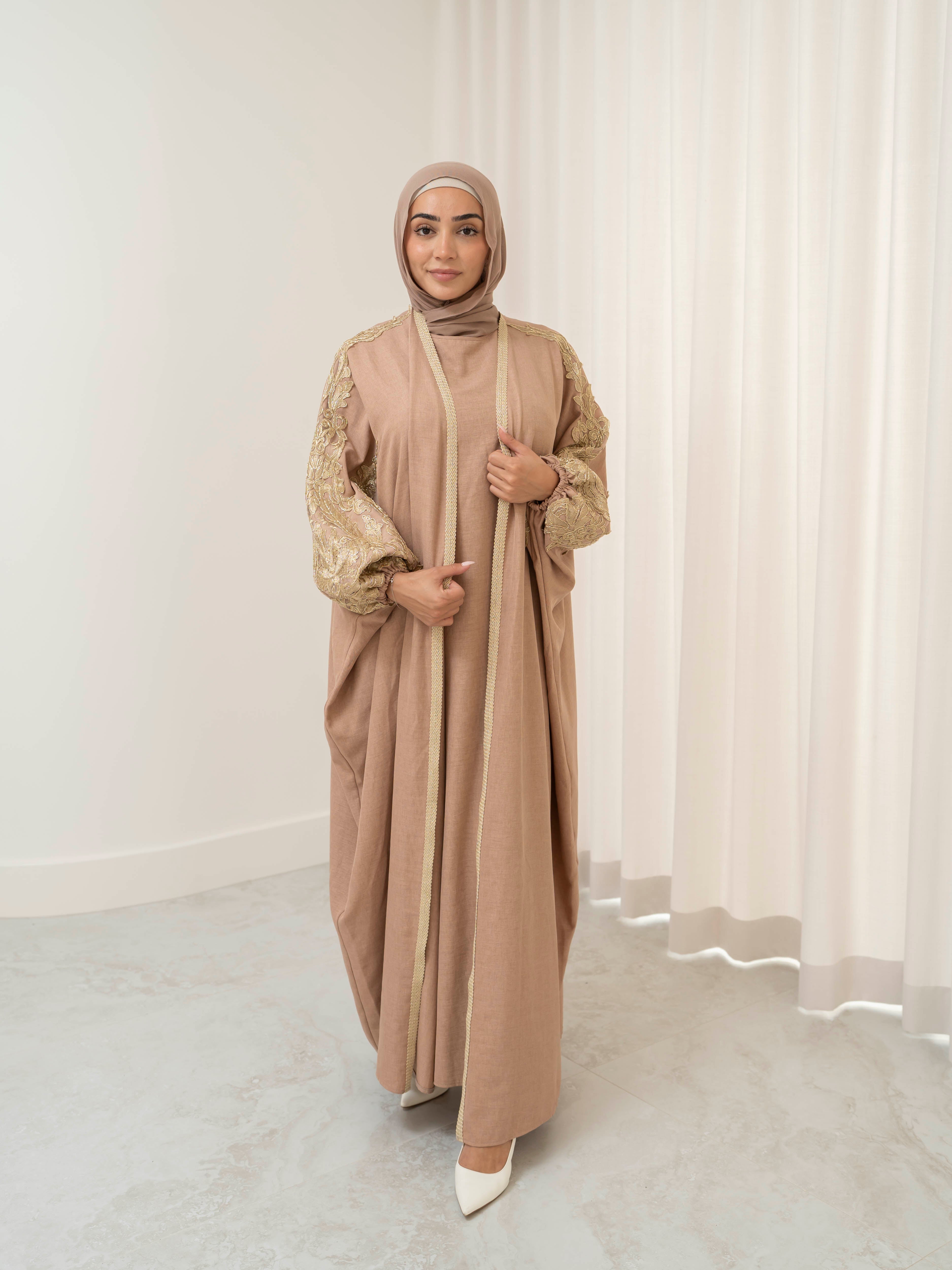 Model wearing the Haya two-piece abaya set featuring a gold-embroidered open abaya layered over an inner dress, styled for a modest and elegant look suitable for Ramadan and Eid.