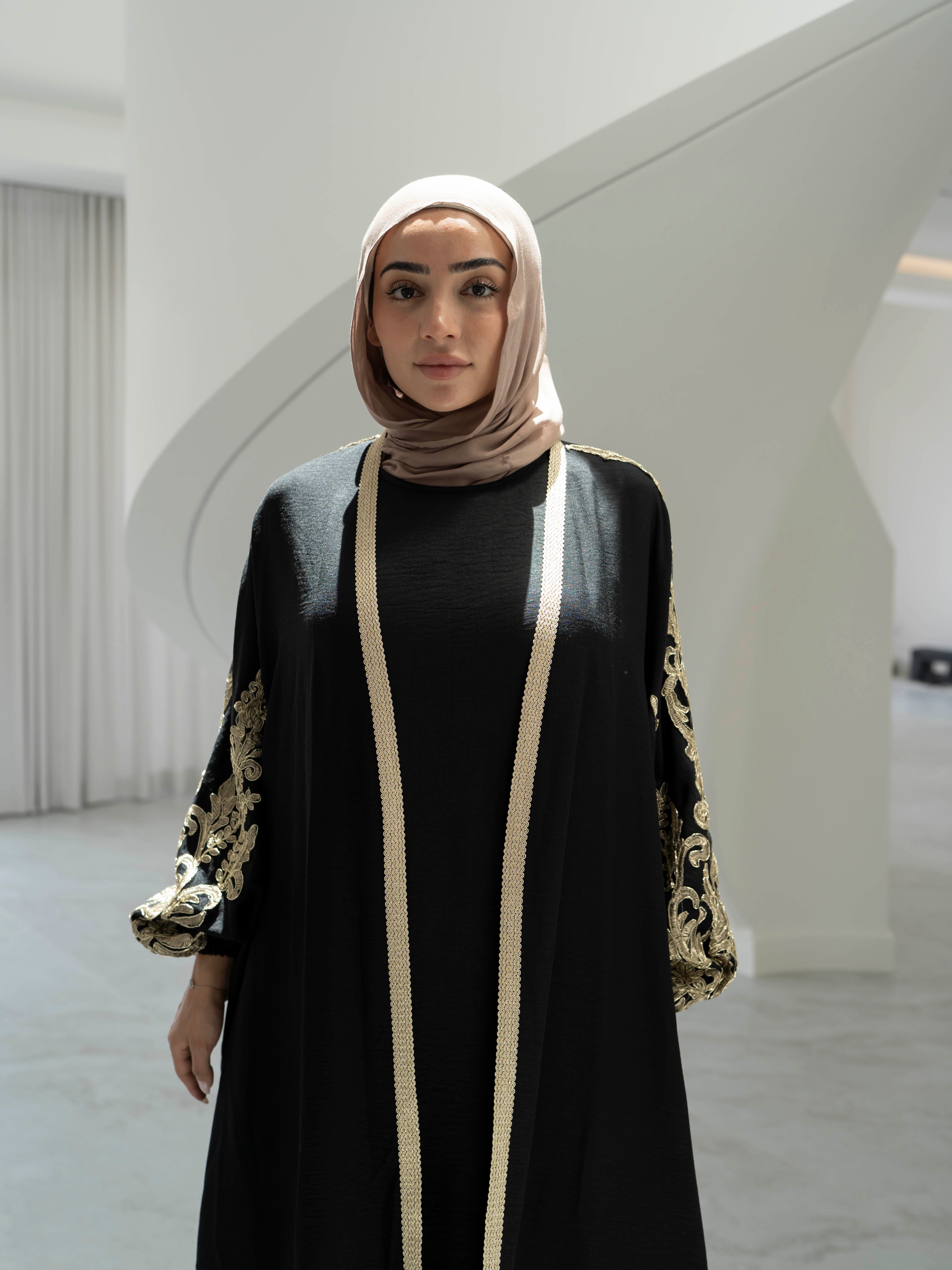 Model wearing the Haya two-piece abaya set featuring a gold-embroidered open abaya layered over an inner dress, styled for a modest and elegant look suitable for Ramadan and Eid.
