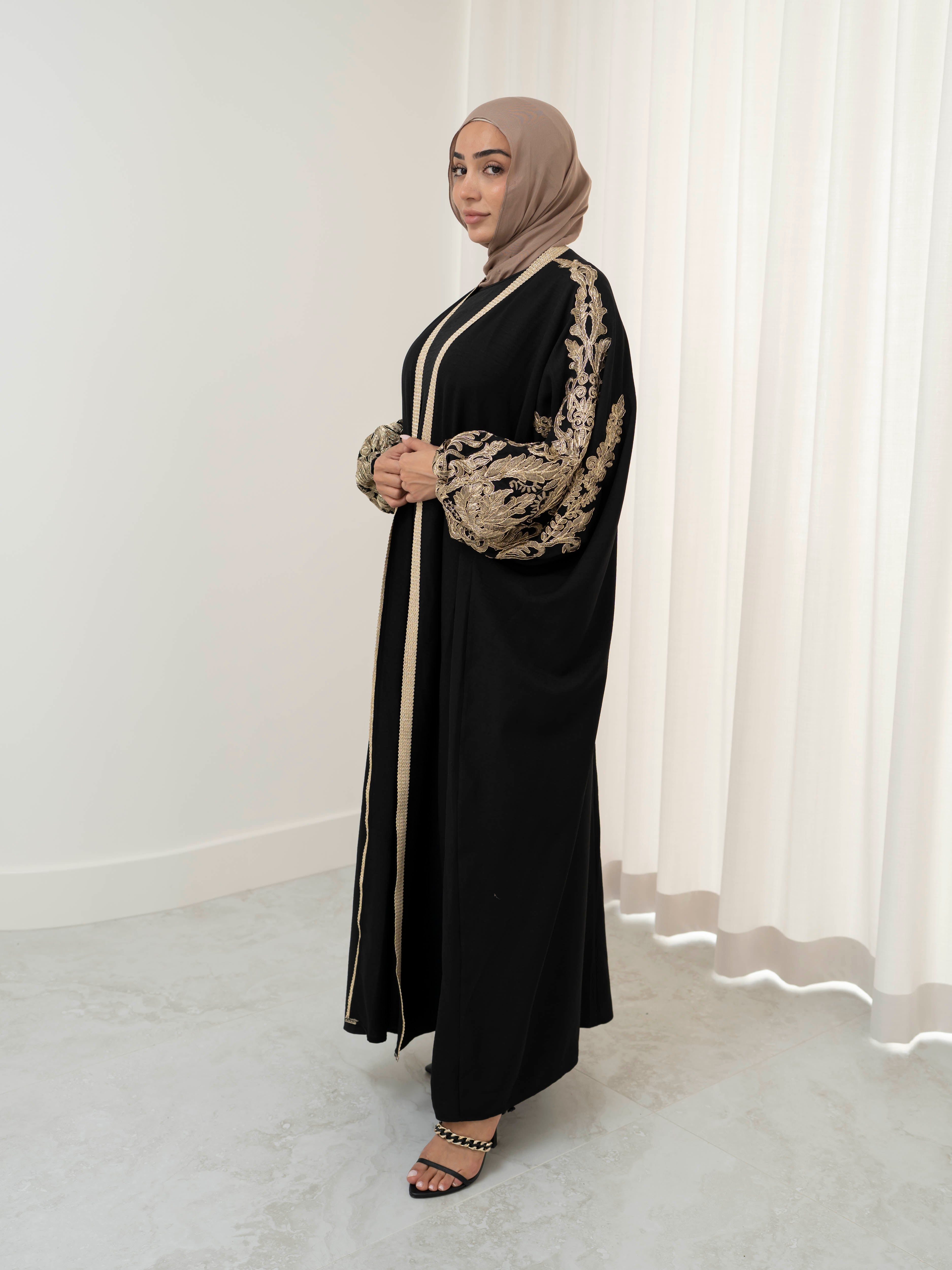Model wearing the Haya two-piece abaya set featuring a gold-embroidered open abaya layered over an inner dress, styled for a modest and elegant look suitable for Ramadan and Eid.