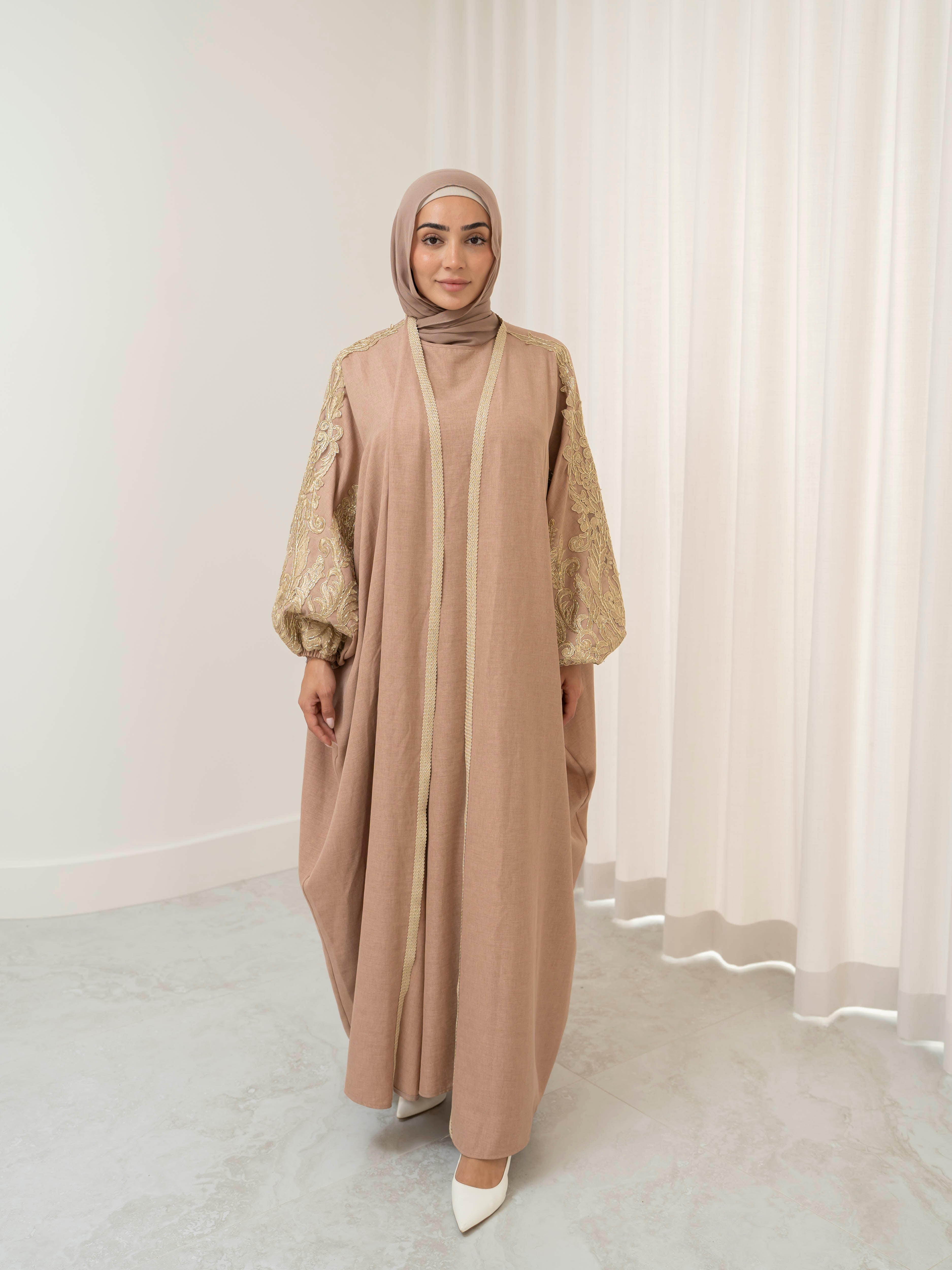 Model wearing the Haya two-piece abaya set featuring a gold-embroidered open abaya layered over an inner dress, styled for a modest and elegant look suitable for Ramadan and Eid.