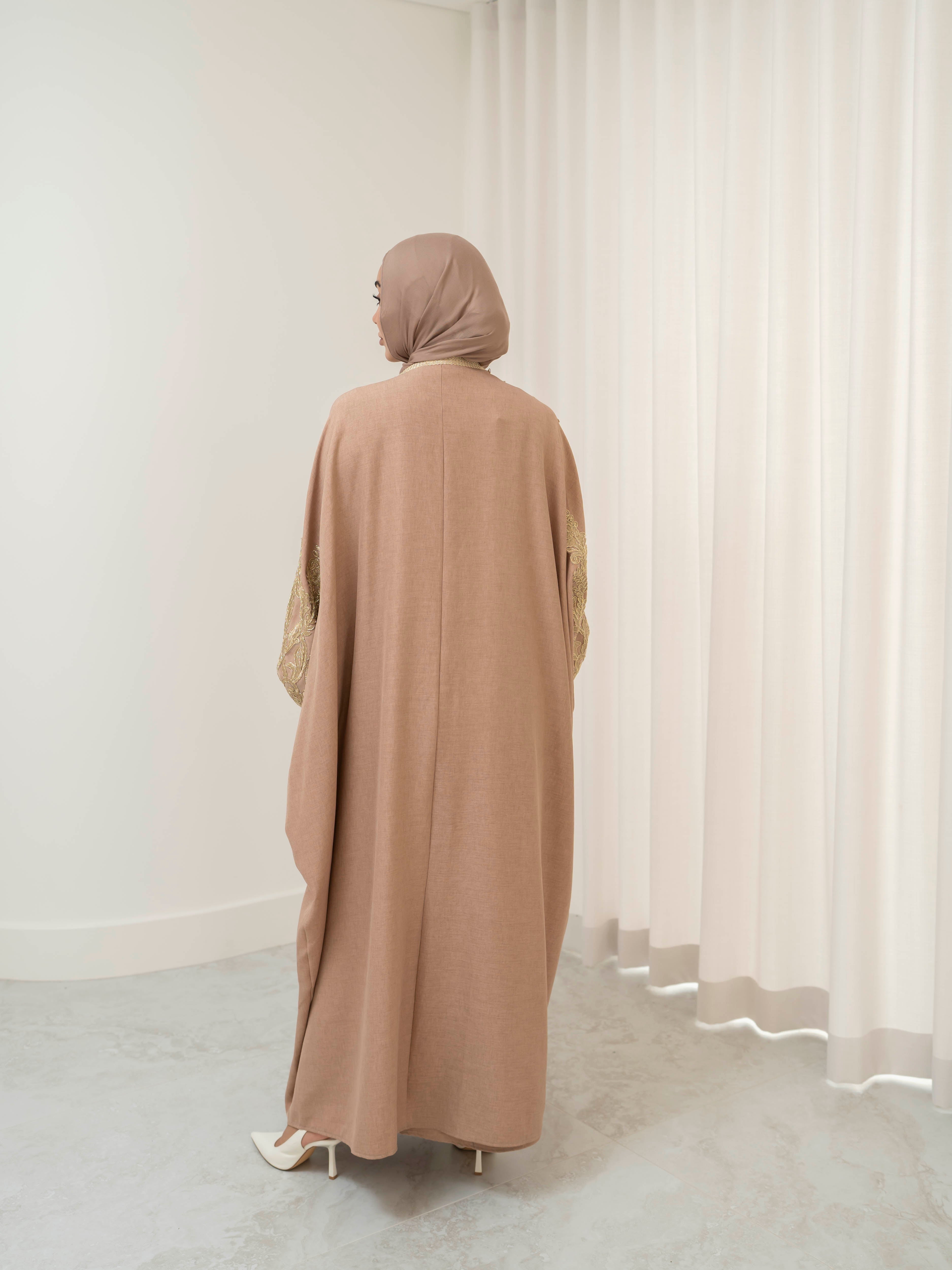 Model wearing the Haya two-piece abaya set featuring a gold-embroidered open abaya layered over an inner dress, styled for a modest and elegant look suitable for Ramadan and Eid.