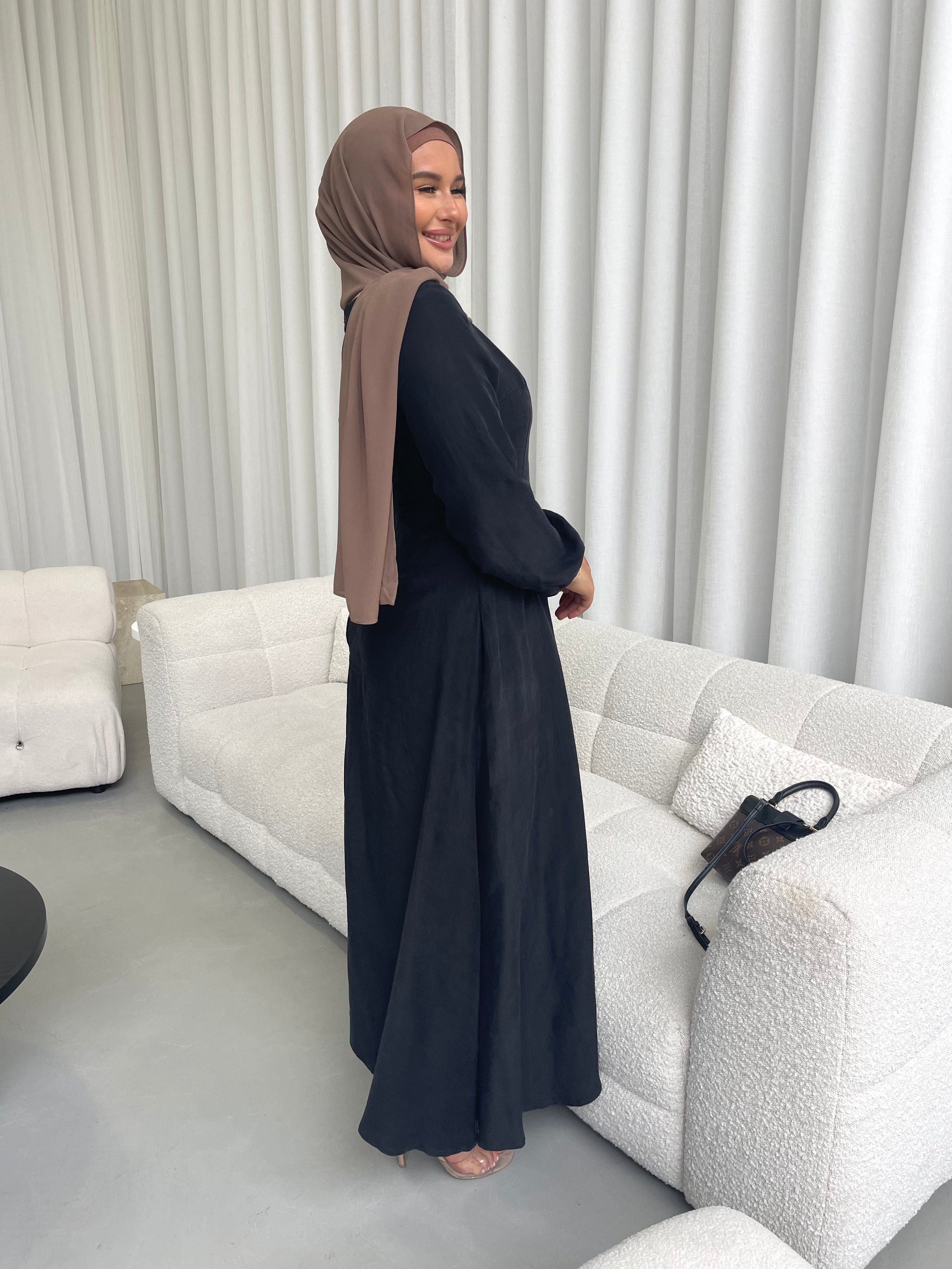 Amira Dress in linen-viscose fabric with long sleeves and a fitted bodice featuring an empire waist and limited stretch. Flows into a loose high-low skirt for an elegant silhouette, suitable for special occasions or styled with heels.