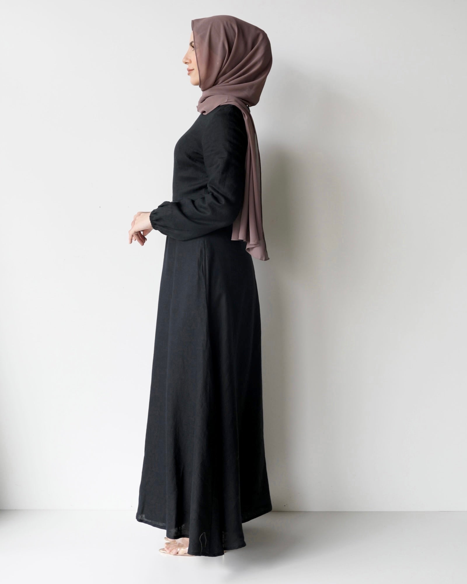 Amira Dress in linen-viscose fabric with long sleeves and a fitted bodice featuring an empire waist and limited stretch. Flows into a loose high-low skirt for an elegant silhouette, suitable for special occasions or styled with heels.