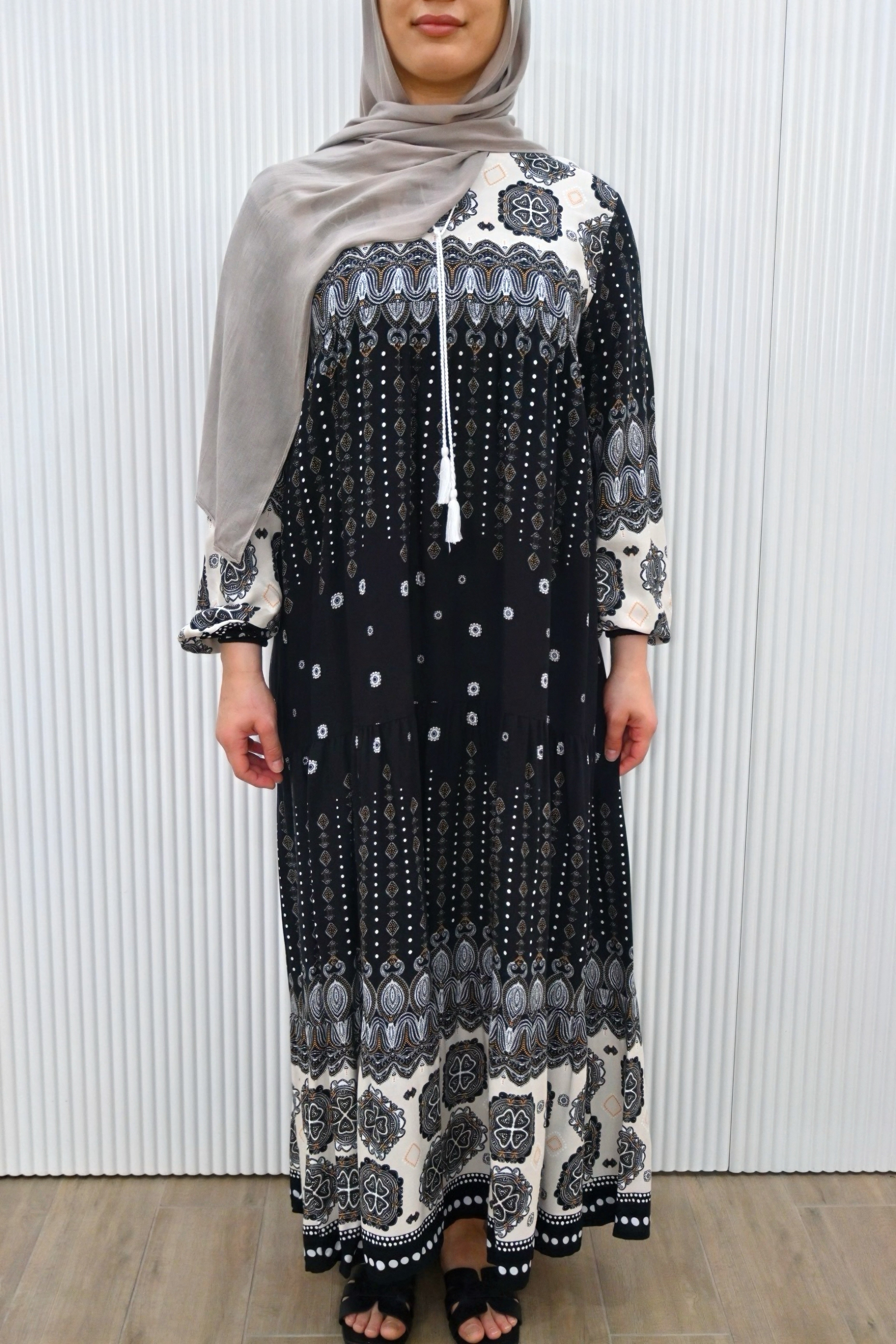 This is a long, loose-fit maxi dress with long sleeves. It features floral and geometric patterns with a flowy gathered design, making it stylish and modest.