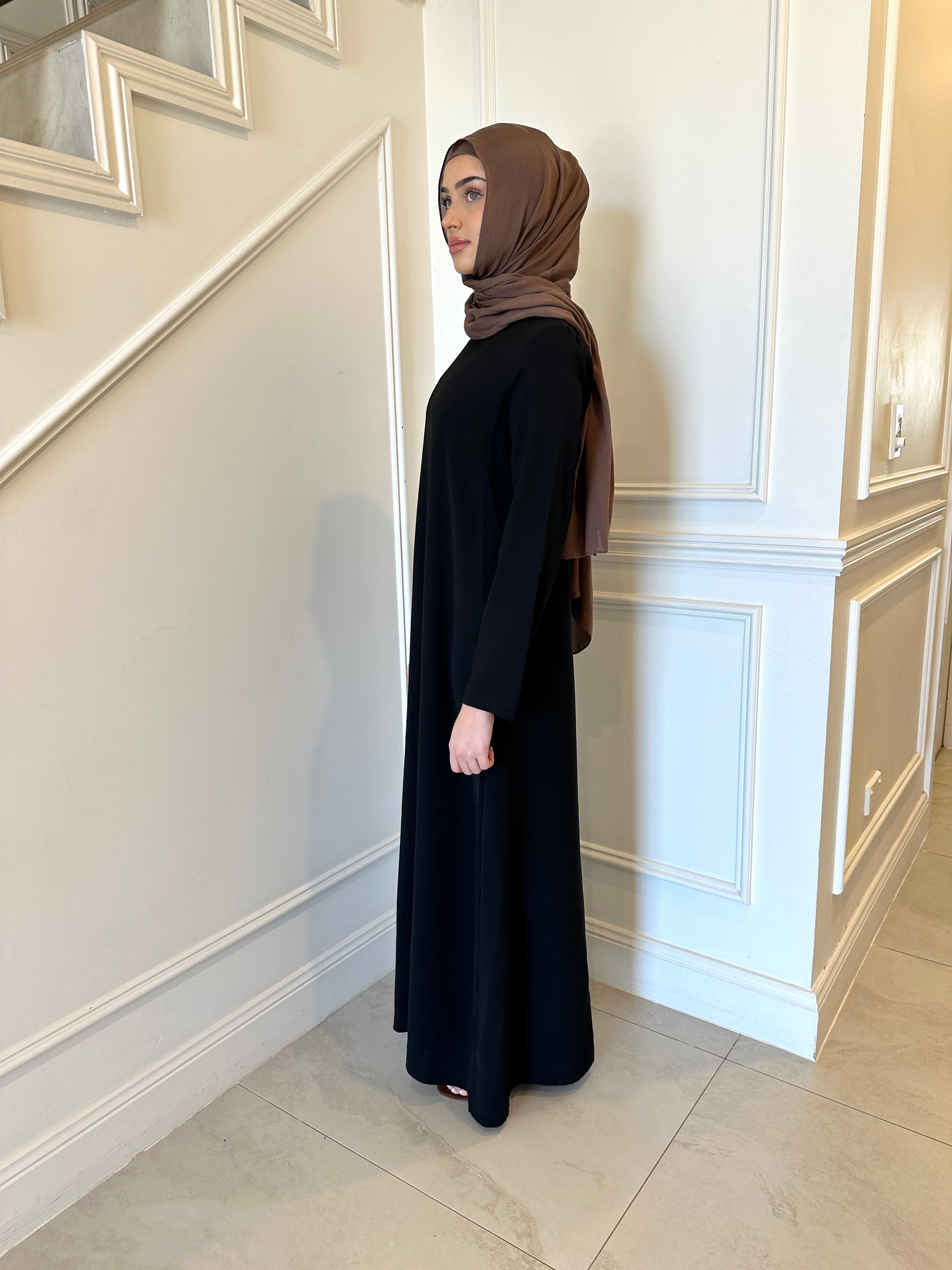 Basic Abaya in a classic straight-cut maxi silhouette with long sleeves and a round neckline. Minimalist design offers modest, polished elegance suitable for everyday wear or special occasions.