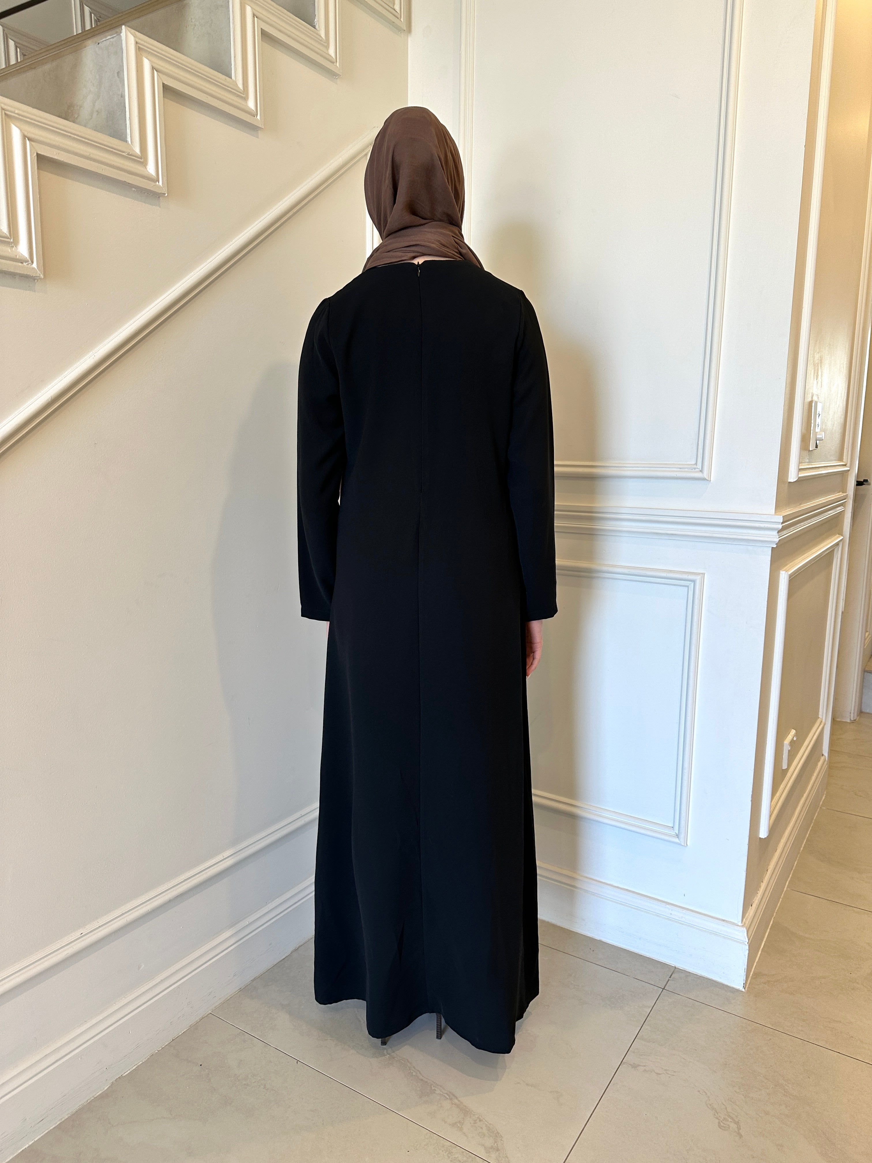 Basic Abaya in a classic straight-cut maxi silhouette with long sleeves and a round neckline. Minimalist design offers modest, polished elegance suitable for everyday wear or special occasions.