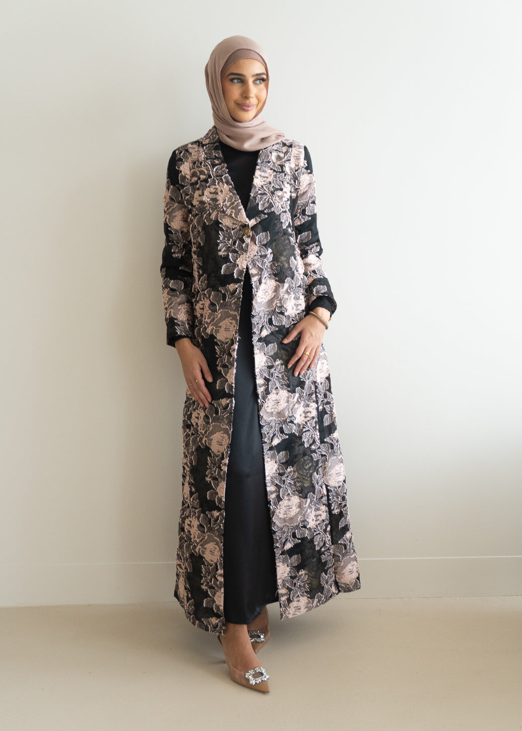 This EDEN JACQUARD COAT- ROSE SET offers both style and functionality. The two-piece ensemble features a stunning sheer coat with intricate floral embroidery, a single button fastening, and notched lapels. 