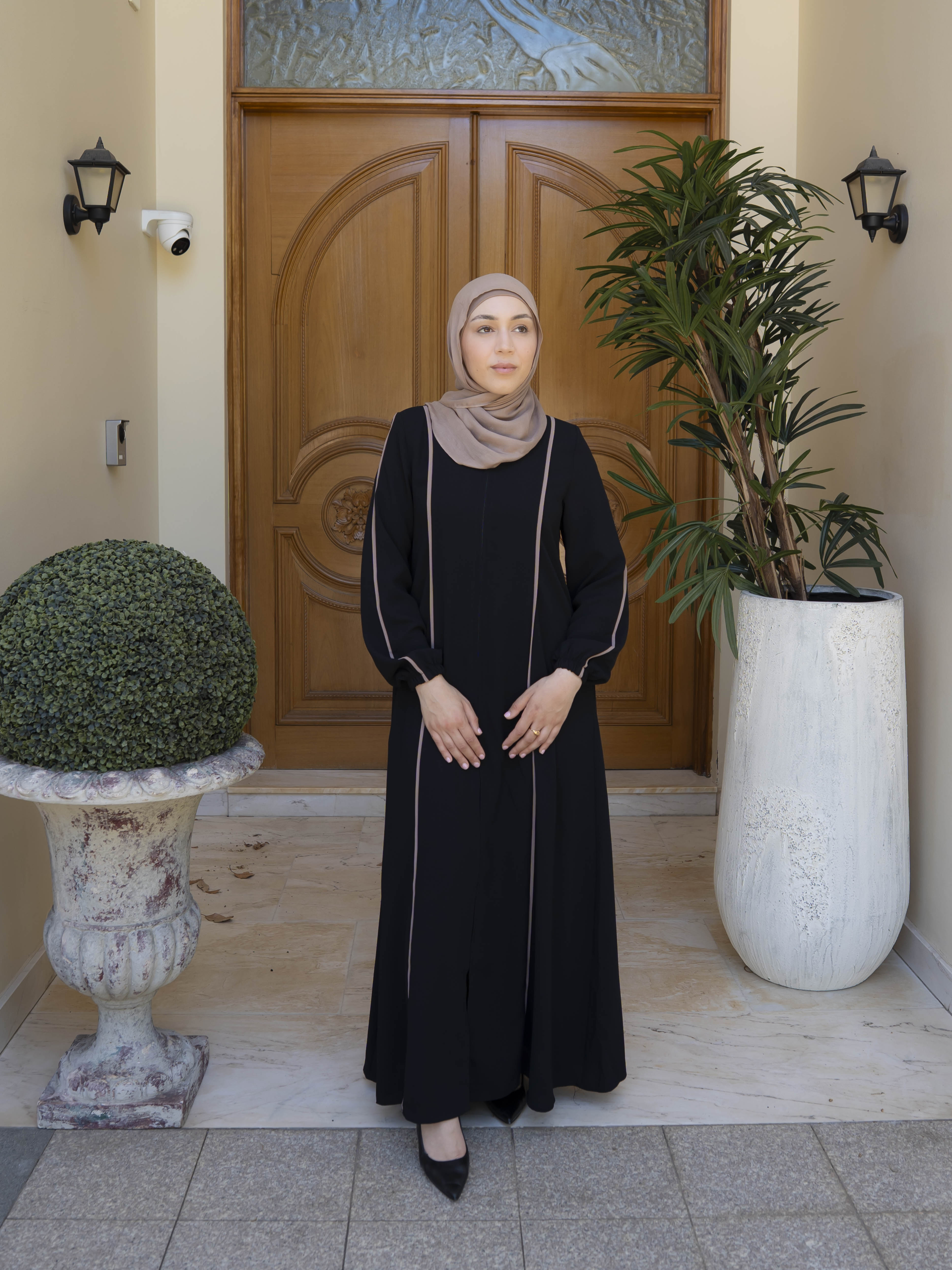 Elara Abaya with a longline, modest silhouette featuring a centre-front concealed zipper and elegant contrast piping. Flowing, structured design offers polished, tailored drape, ideal for everyday wear, gatherings, or Ramadan.