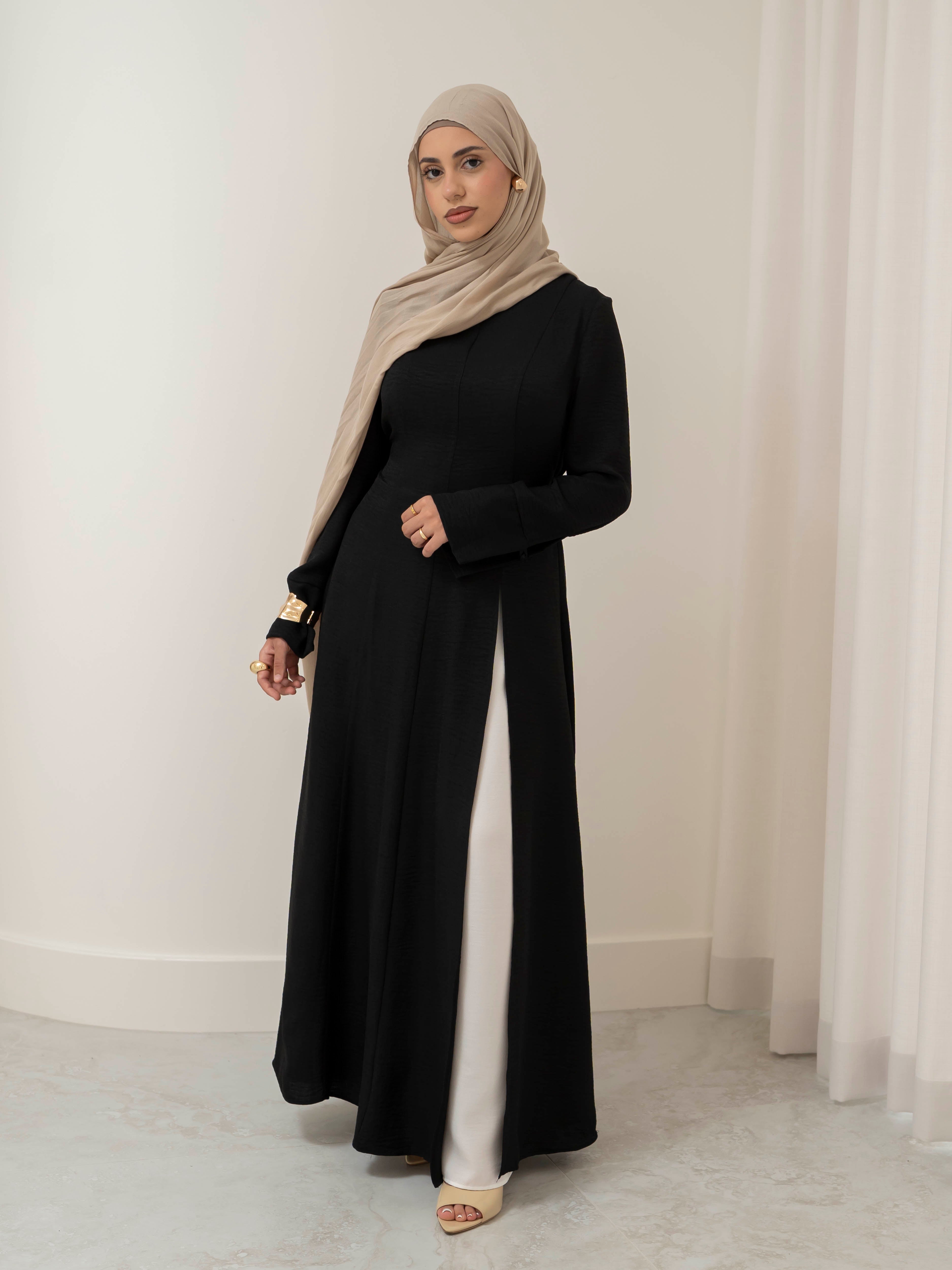Isla Panelled Dress Set, a two-piece outfit with a tailored outer dress and contrasting inner skirt in a structured, full-length design. Features long sleeves with cuffs, an adjustable waist tie, and lightweight fabric with elegant drape, offering a modest and polished look for formal occasions or Eid.