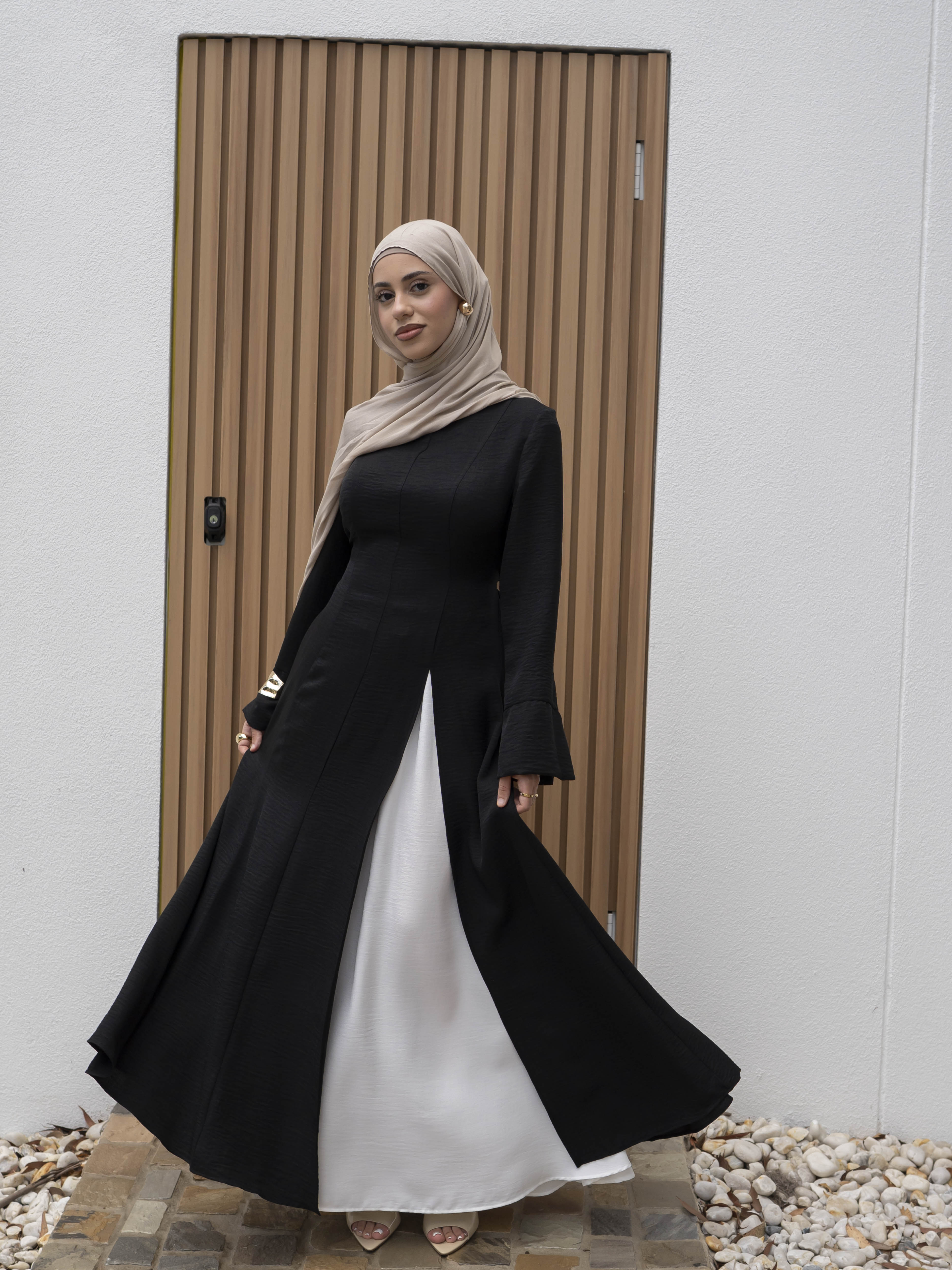 Isla Panelled Dress Set, a two-piece outfit with a tailored outer dress and contrasting inner skirt in a structured, full-length design. Features long sleeves with cuffs, an adjustable waist tie, and lightweight fabric with elegant drape, offering a modest and polished look for formal occasions or Eid.