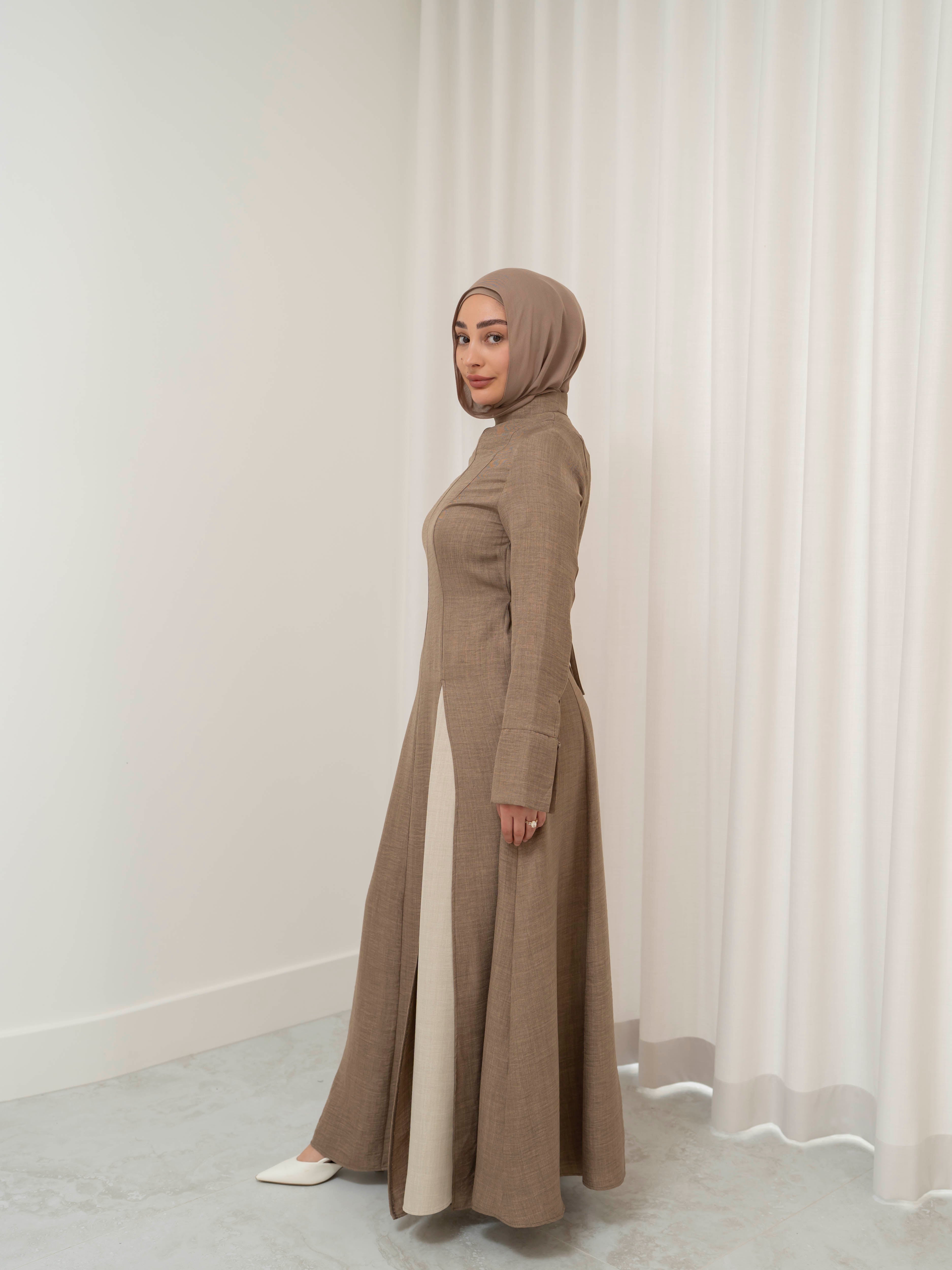 Isla Panelled Dress Set, a two-piece outfit with a tailored outer dress and contrasting inner skirt in a structured, full-length design. Features long sleeves with cuffs, an adjustable waist tie, and lightweight fabric with elegant drape, offering a modest and polished look for formal occasions or Eid.