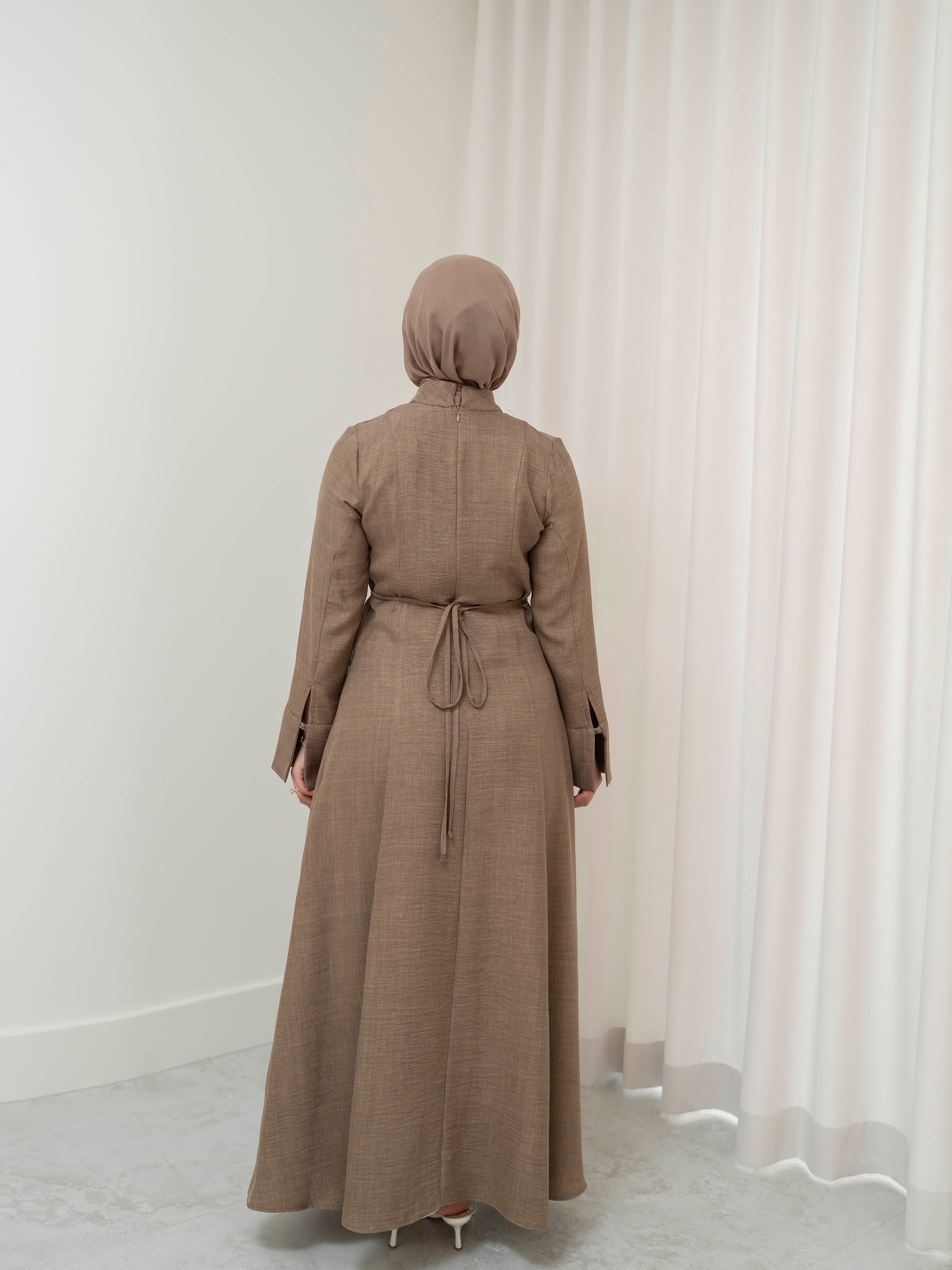 Isla Panelled Dress Set, a two-piece outfit with a tailored outer dress and contrasting inner skirt in a structured, full-length design. Features long sleeves with cuffs, an adjustable waist tie, and lightweight fabric with elegant drape, offering a modest and polished look for formal occasions or Eid.