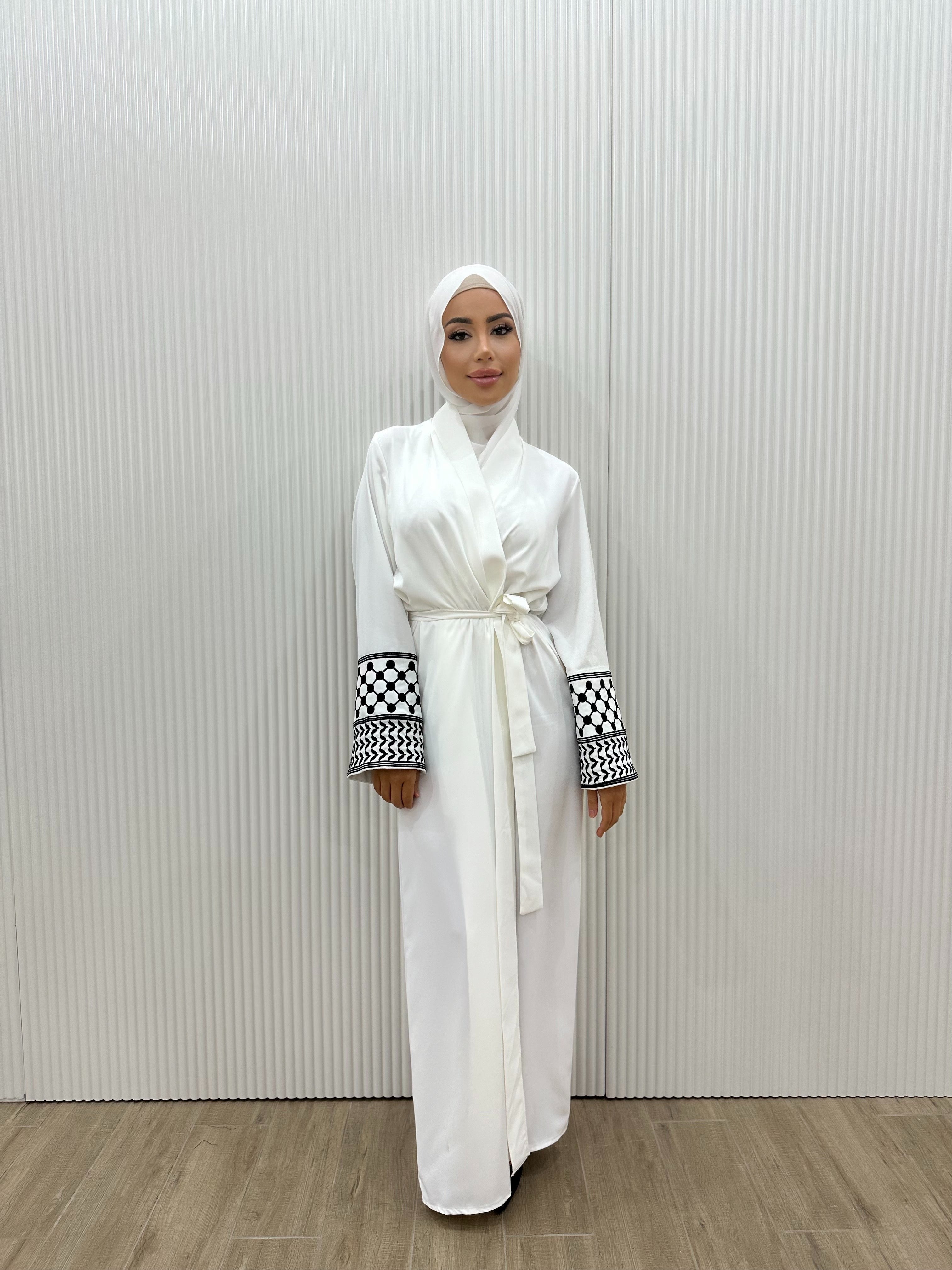 Show your support for Palestine with the KEFFIYEH SLEEVE ABAYA. With signature Palestinian craft printed on the wide sleeve cuffs, this dress effortlessly combines modesty and comfort. The wrap-inspired silhouette features a self-fastening tie wrap, maxi length hem. Wear yours to public social gatherings to show where you stand!&nbsp;