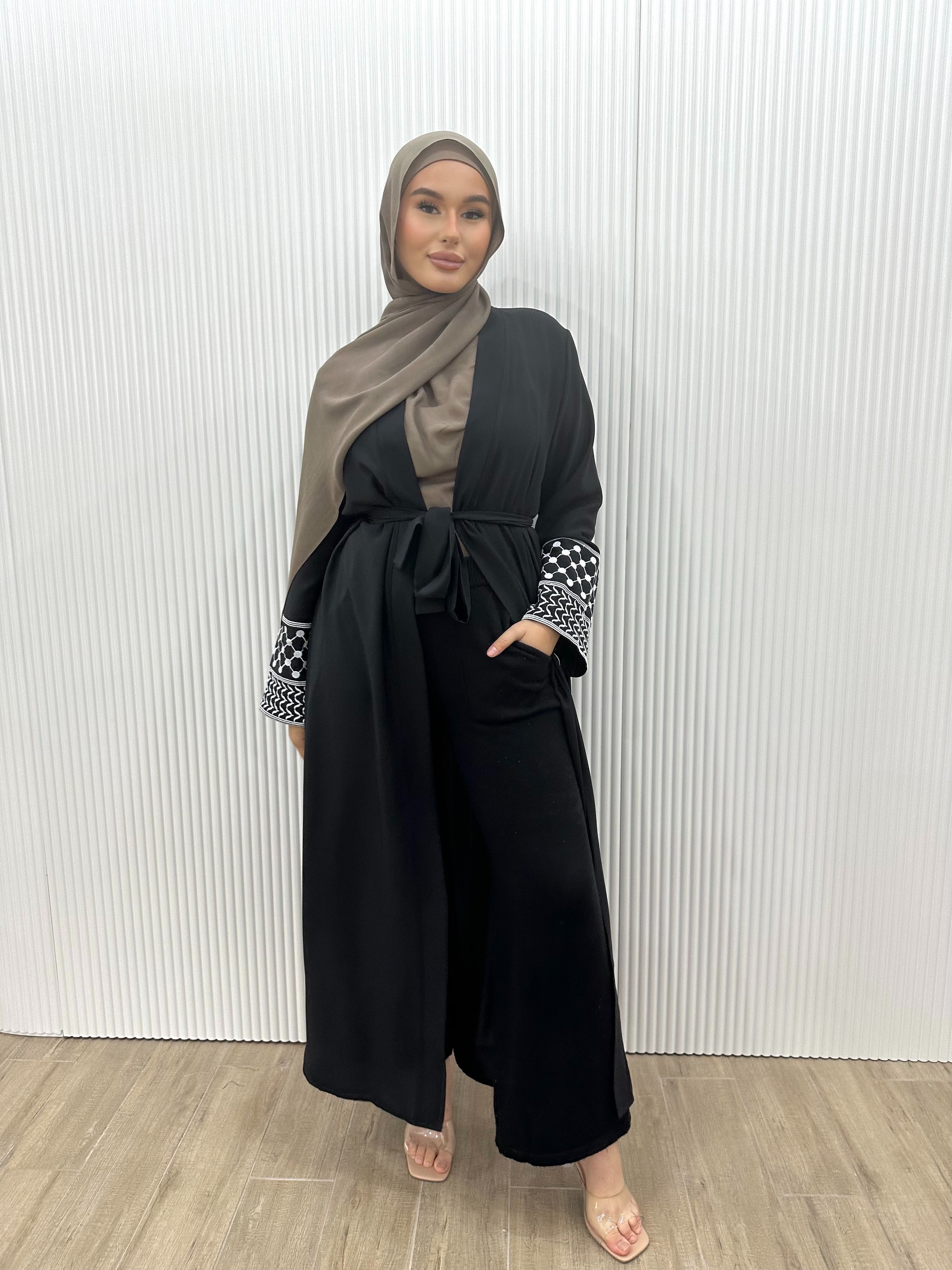 Show your support for Palestine with the KEFFIYEH SLEEVE ABAYA. With signature Palestinian craft printed on the wide sleeve cuffs, this dress effortlessly combines modesty and comfort. The wrap-inspired silhouette features a self-fastening tie wrap, maxi length hem. Wear yours to public social gatherings to show where you stand!&nbsp;