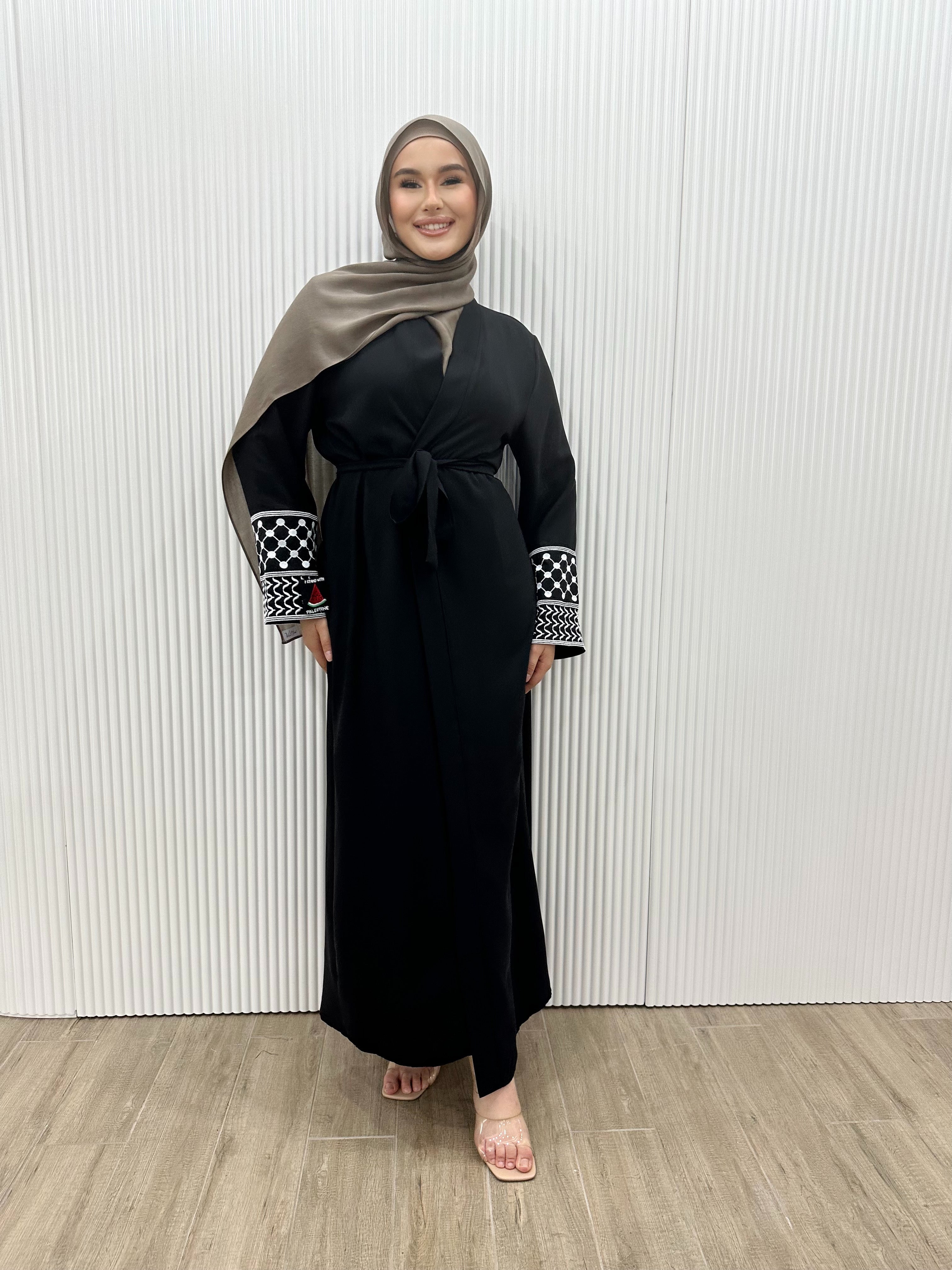 Show your support for Palestine with the KEFFIYEH SLEEVE ABAYA. With signature Palestinian craft printed on the wide sleeve cuffs, this dress effortlessly combines modesty and comfort. The wrap-inspired silhouette features a self-fastening tie wrap, maxi length hem. Wear yours to public social gatherings to show where you stand!&nbsp;